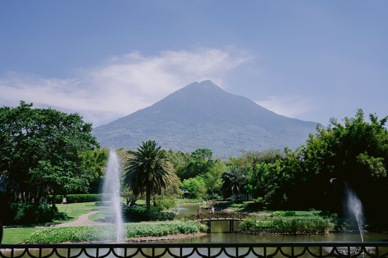 Scenic mountain landscape with fountains and palm trees in a manicured tropical garden.