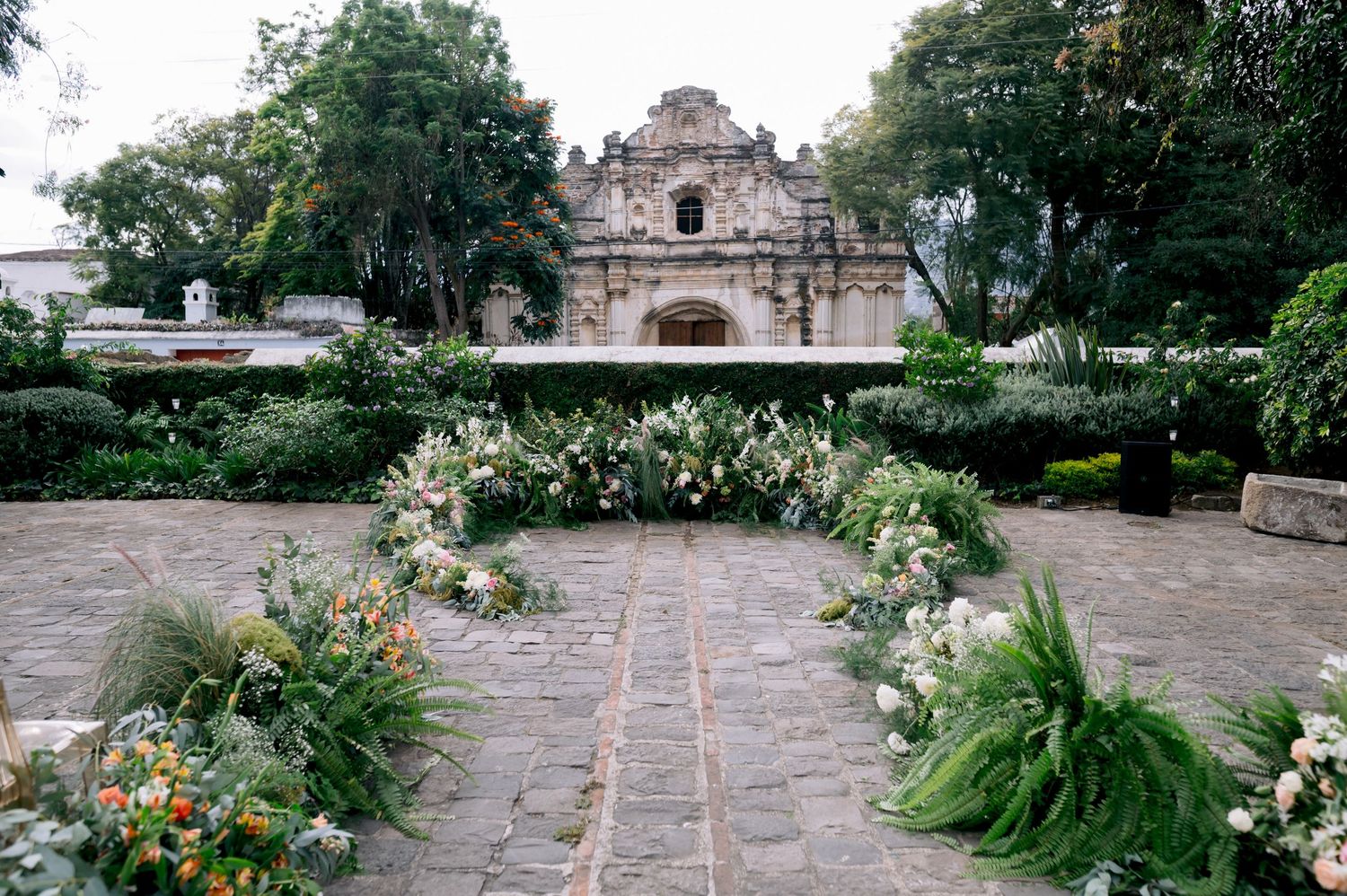 Stone pathway leading to ancient church entrance with garden flowers lining the sides.