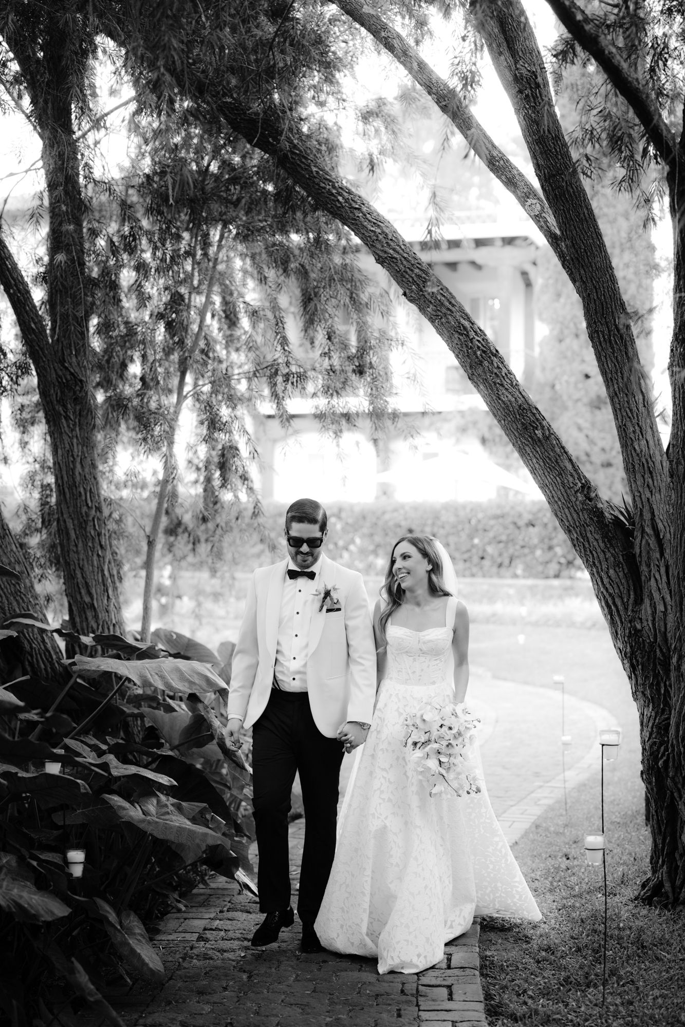 A black and white wedding portrait captured under drooping tree branches.