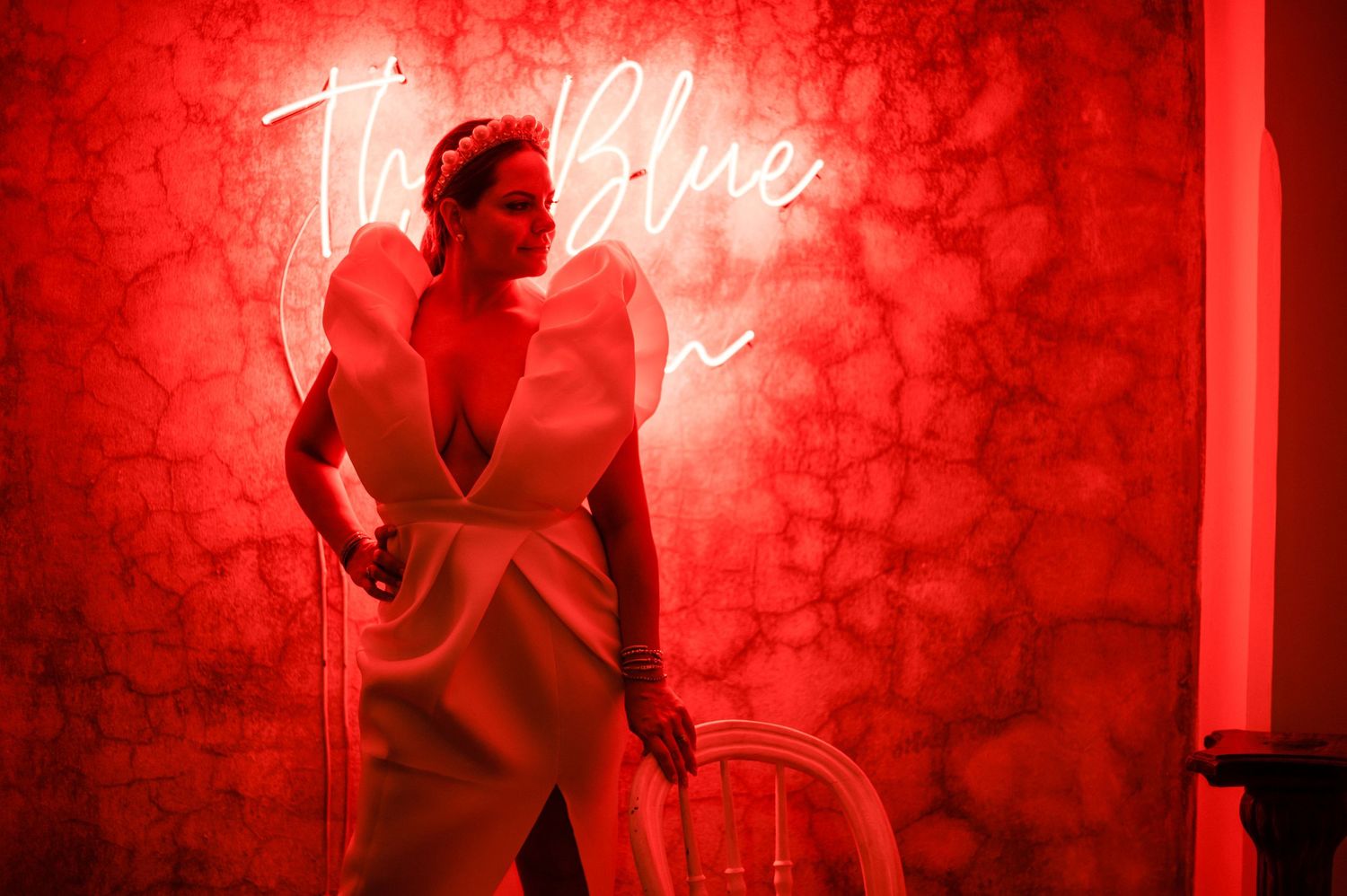 Wedding guests dance under dramatic red lighting during an evening reception celebration.