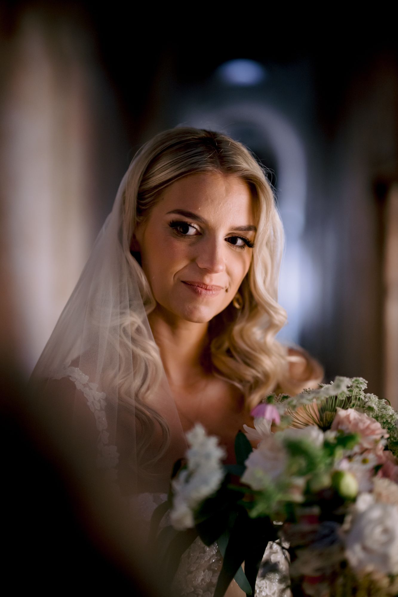 A close-up bridal portrait featuring soft waves, flowing veil, and natural bridal makeup.