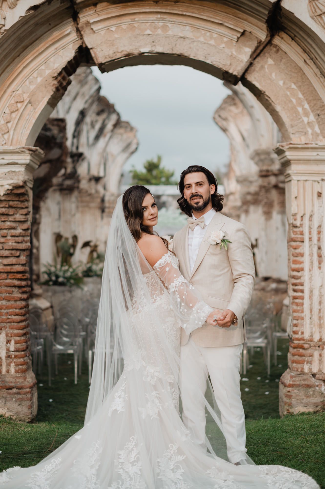Elegant couple shares intimate dance moves under historic stone archways during their wedding celebration.