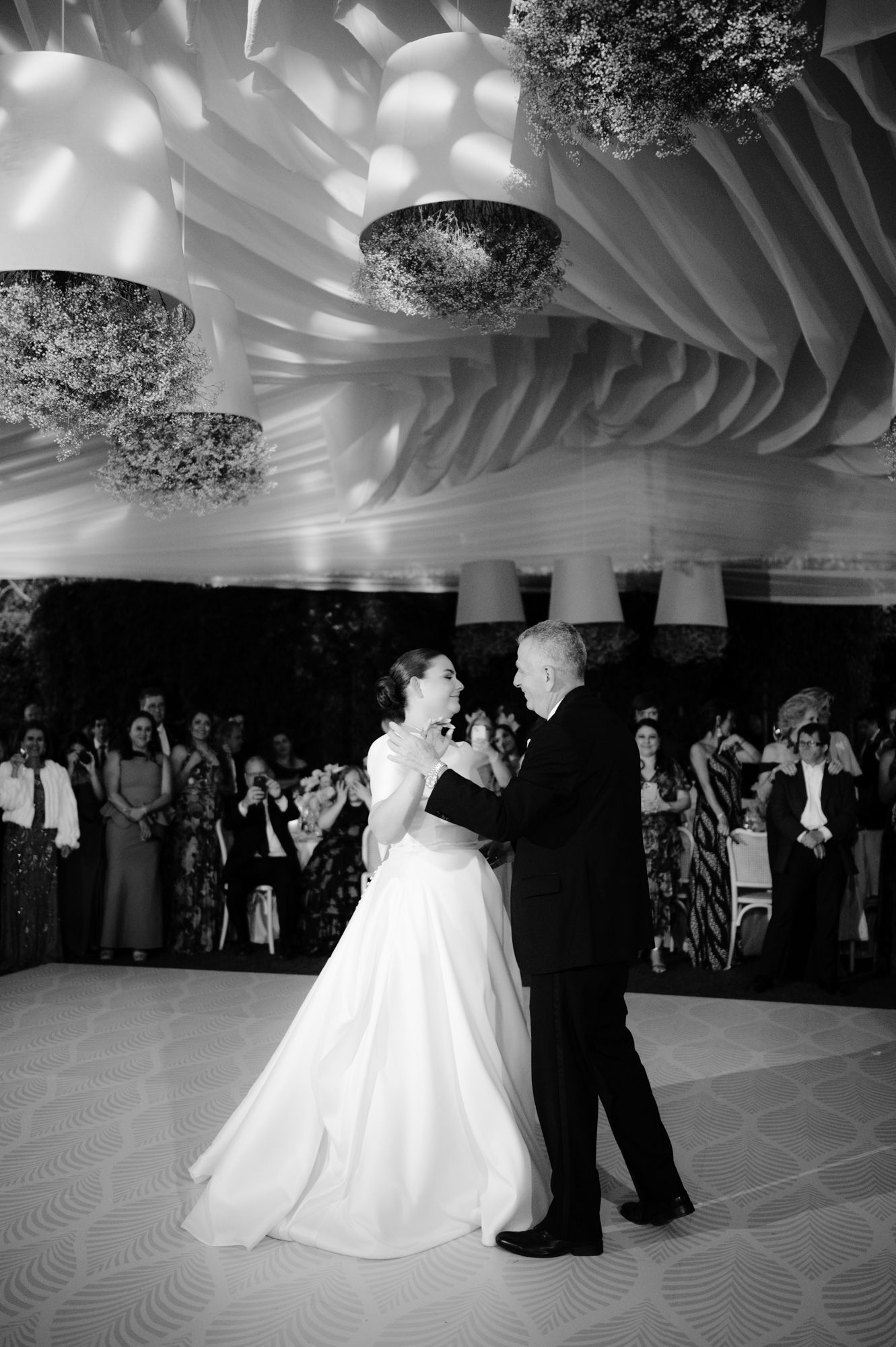 A romantic dance moment captured in black and white beneath elegant draped ceiling decor.