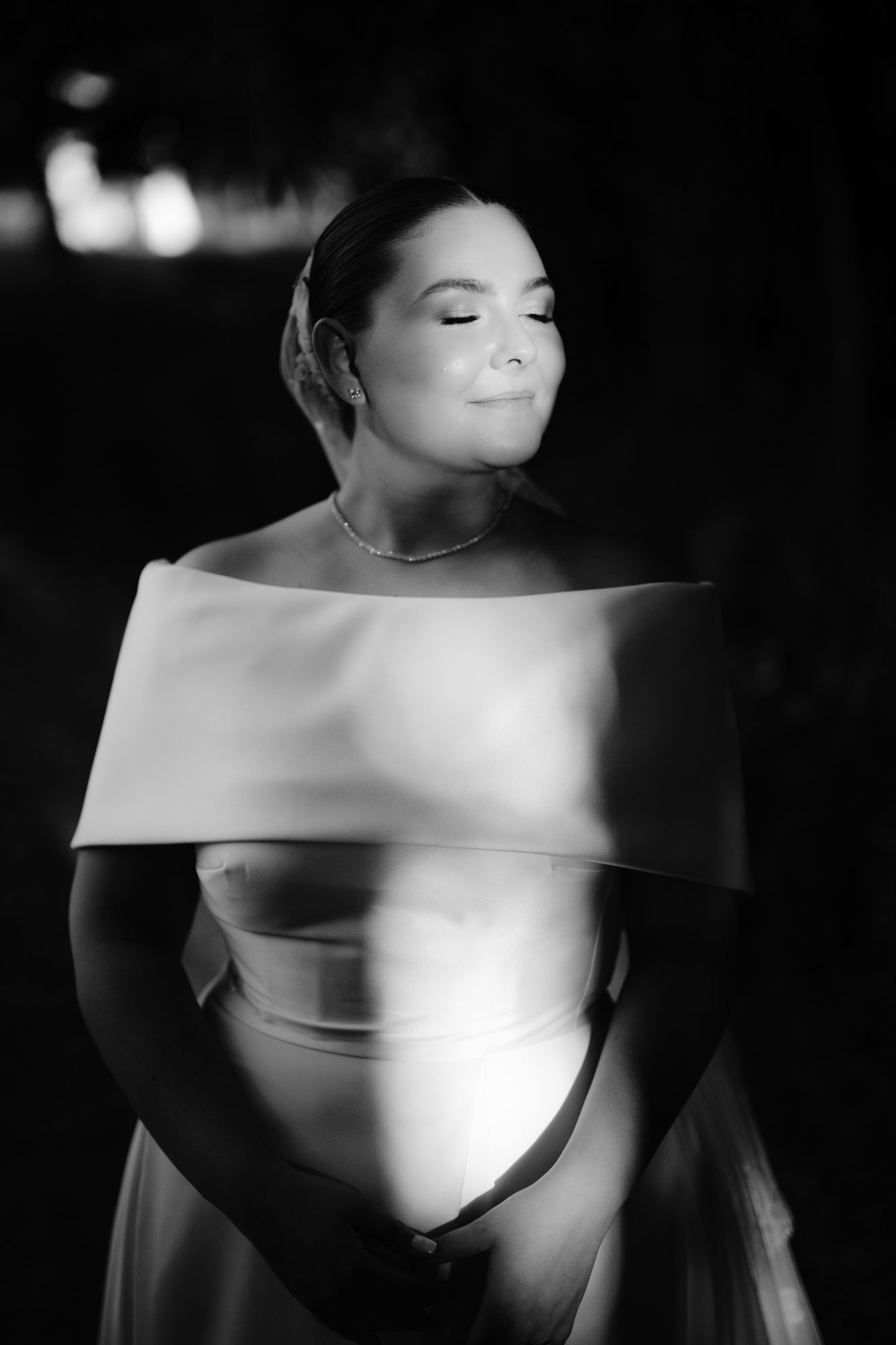 An elegant black and white bridal portrait featuring an off-shoulder wedding gown.