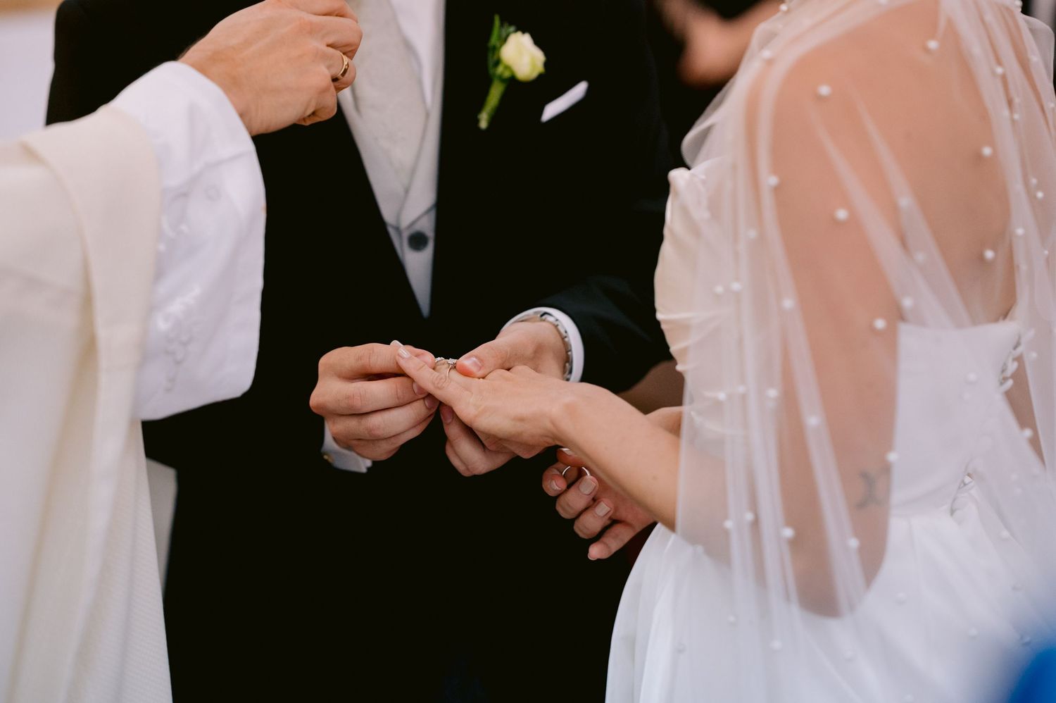 Close-up of wedding ring exchange between bride and groom during traditional ceremony.