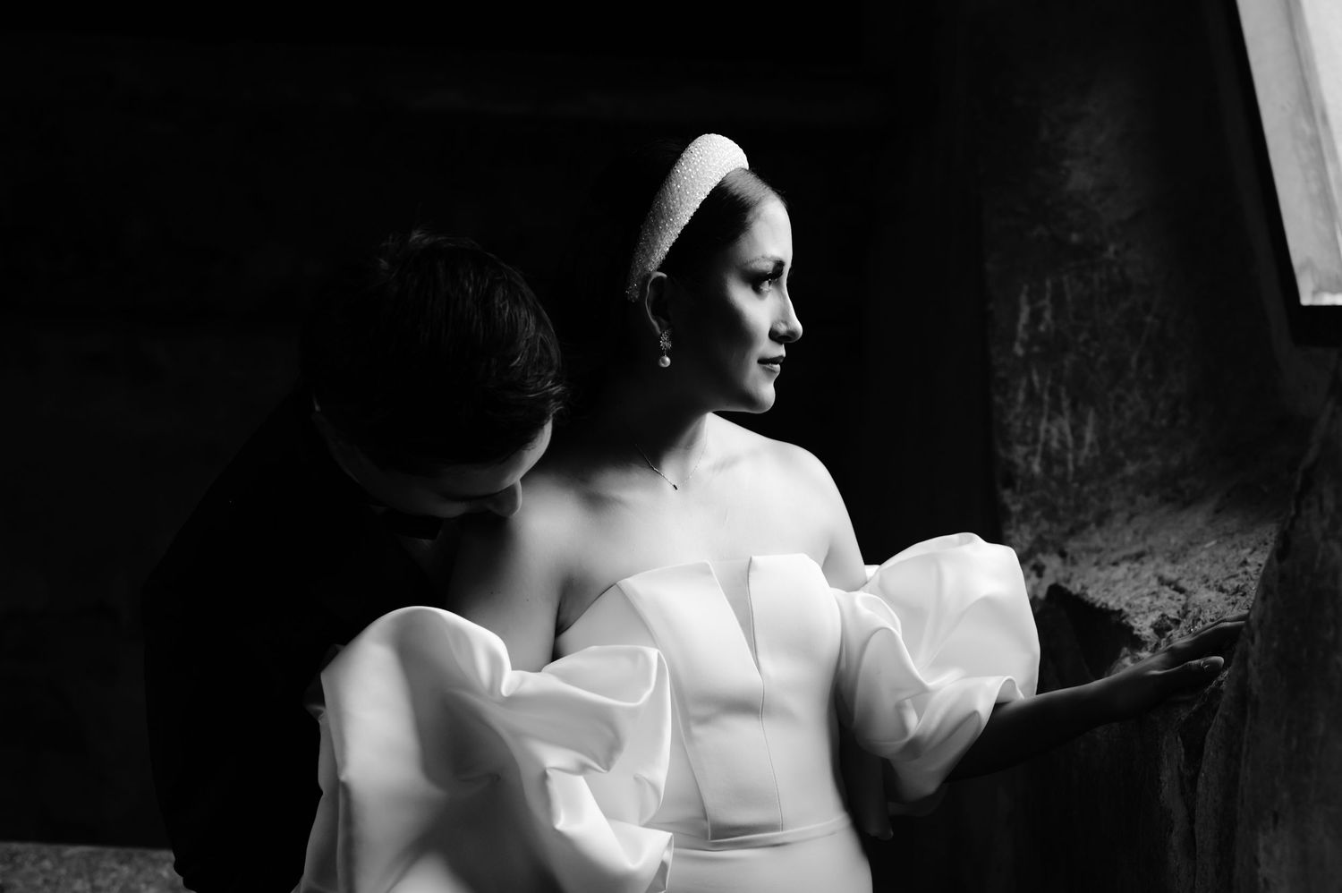 An artistic black and white portrait captures the bride's silhouette in her wedding dress.