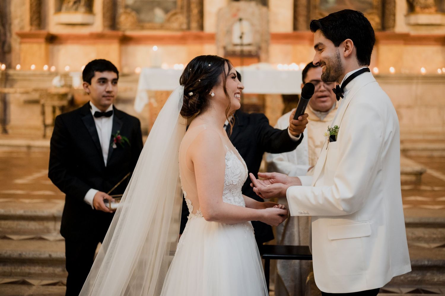 Intimate wedding ceremony moment in an elegant church with religious artwork in the background.