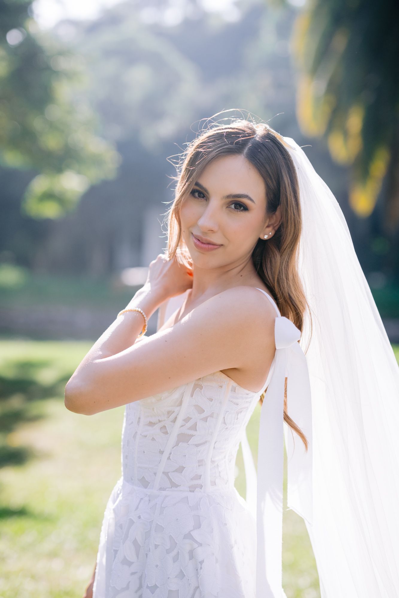 Bridal portraits in soft natural lighting showcase an elegant lace wedding gown and flowing veil.