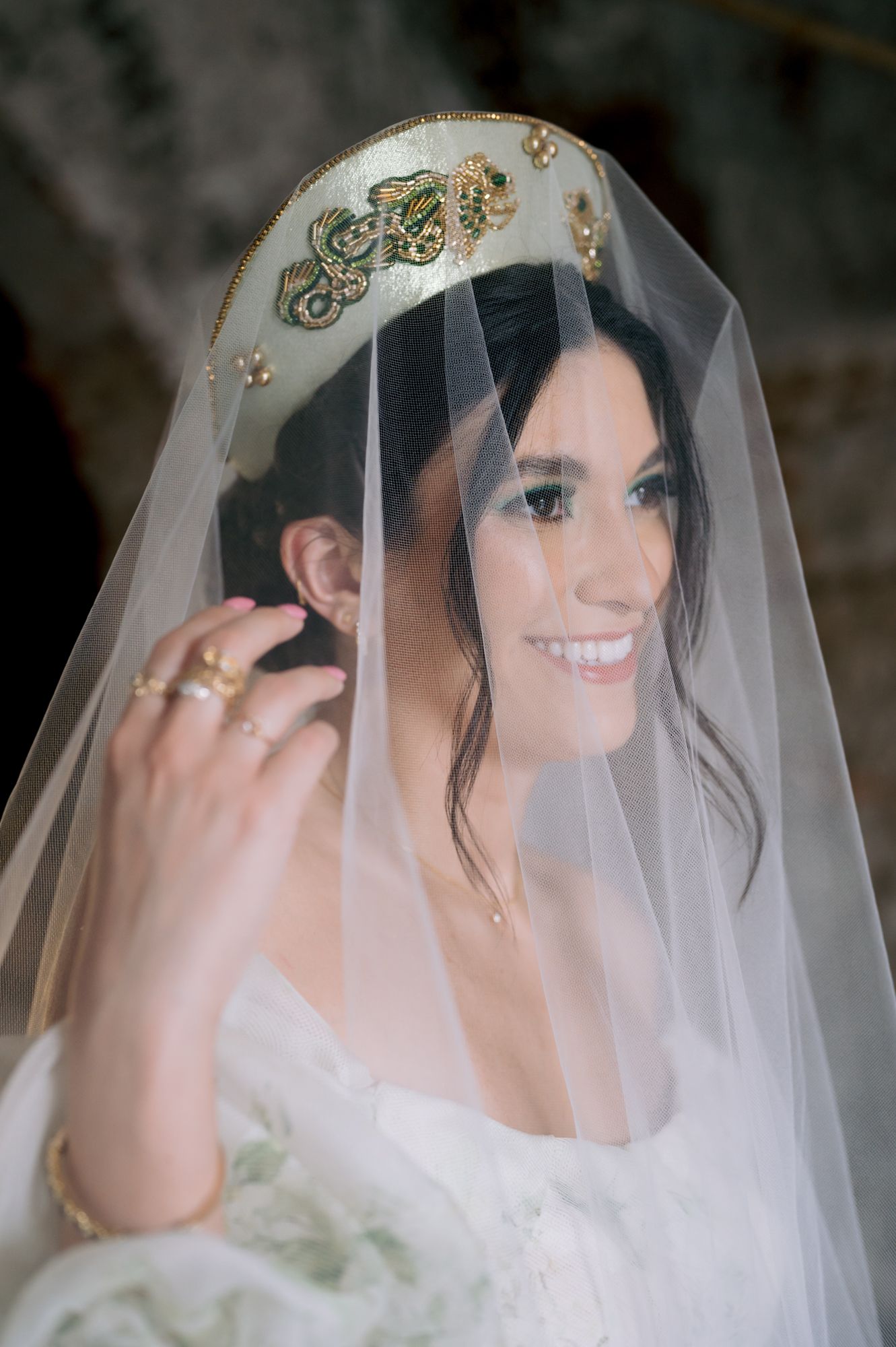 Close-up wedding portrait showing delicate gold crown details and sheer veil against soft lighting.