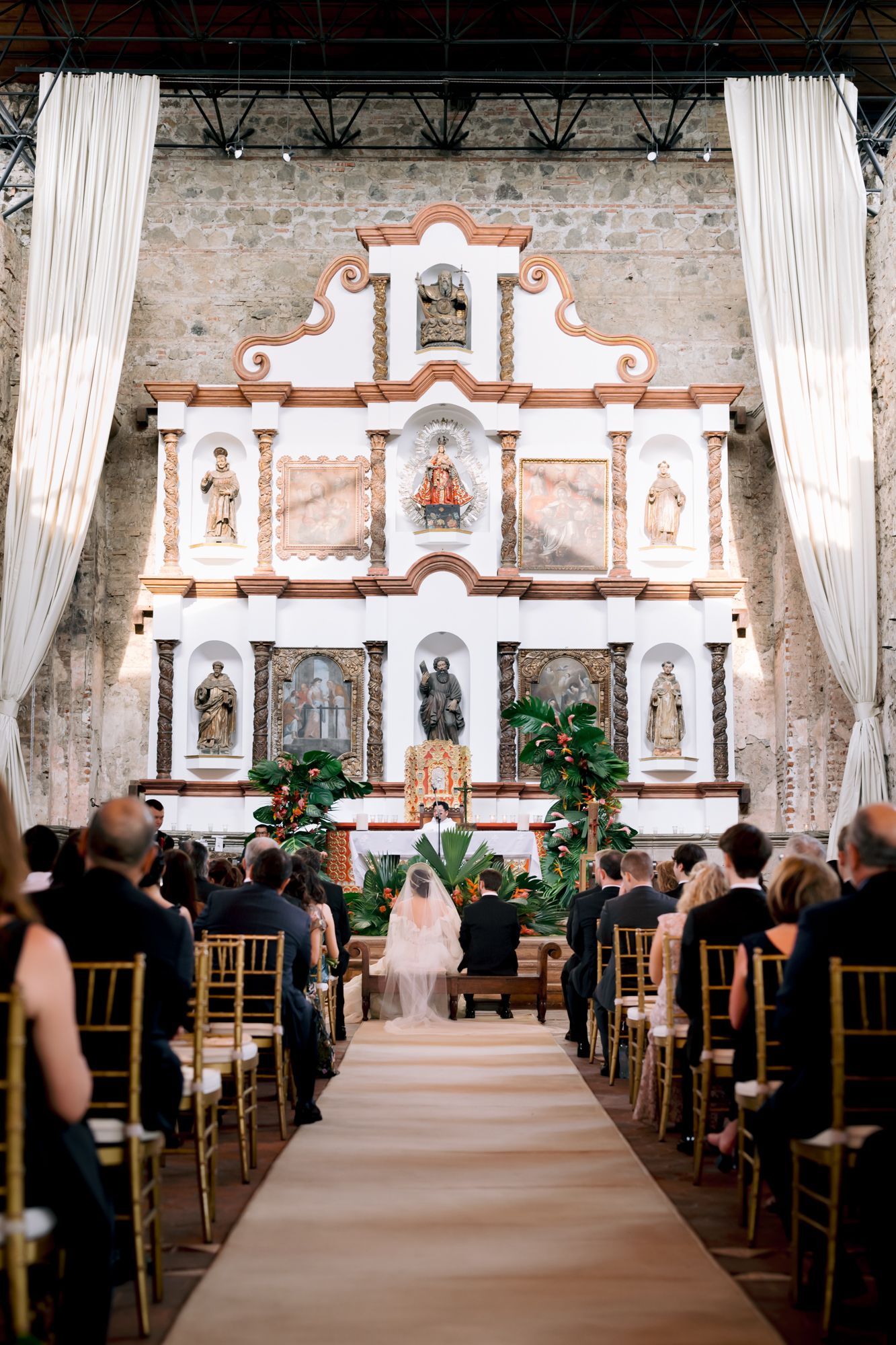 Beautiful Catholic church altar with ornate white and terracotta decorations during an elegant wedding ceremony.