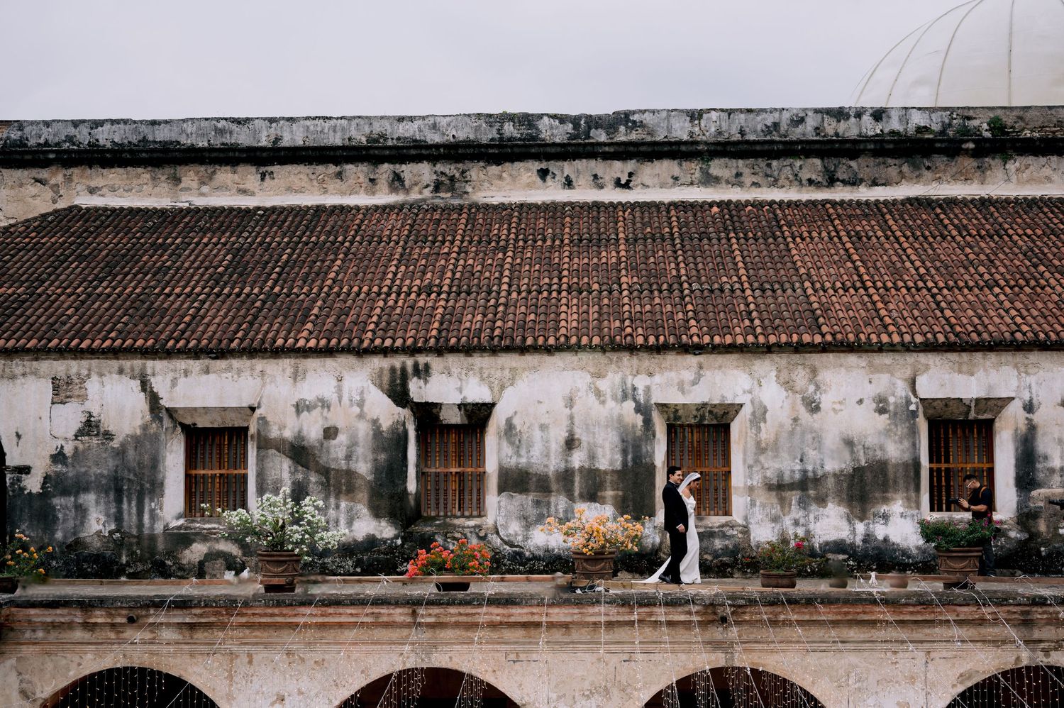 A wedding scene at an old colonial building with weathered walls and arched corridors.