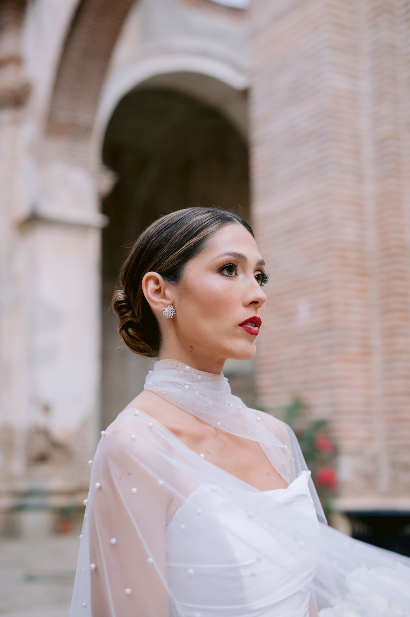 Elegant bridal portrait featuring sleek updo and sheer high-neck cape detail.