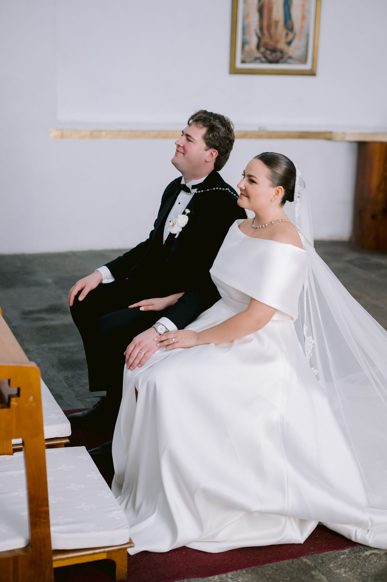 A bride and groom share a candid moment while seated during their traditional church wedding ceremony.