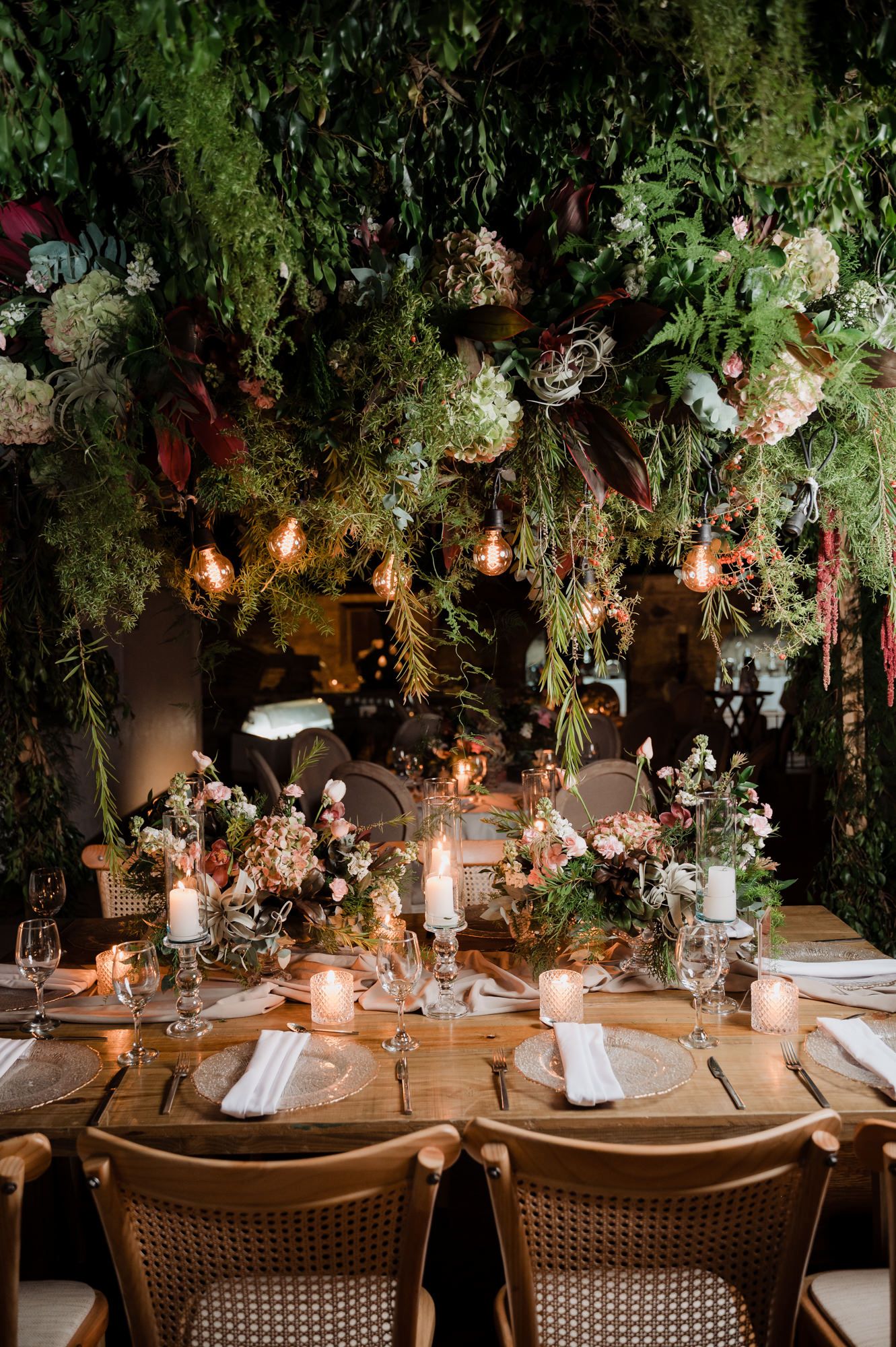 Enchanting wedding reception table decorated with lush greenery, candlelight and floral arrangements in a romantic setting.