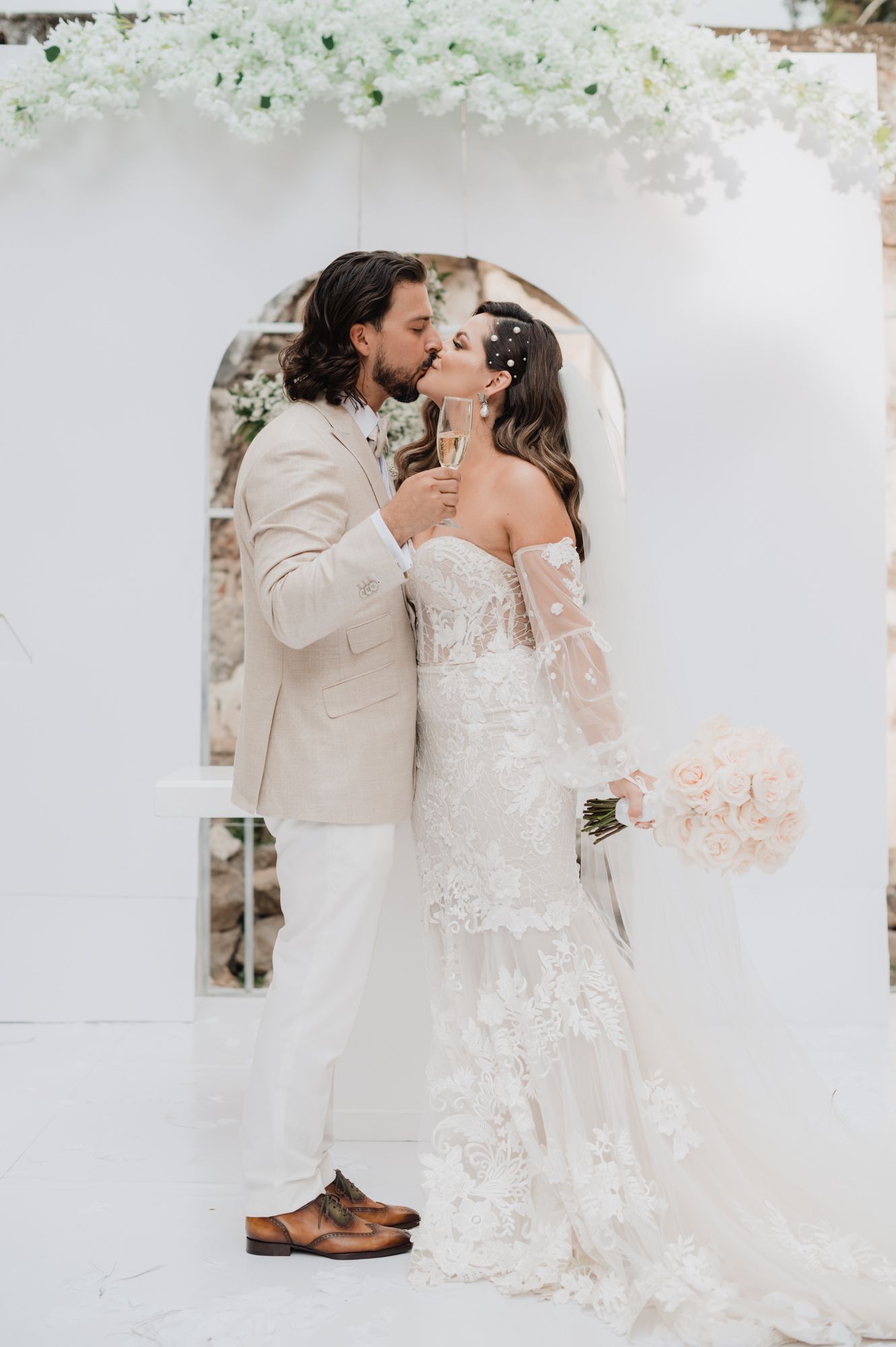 A romantic wedding couple shares intimate kisses in a series of soft, ethereal photos with white and blush tones.