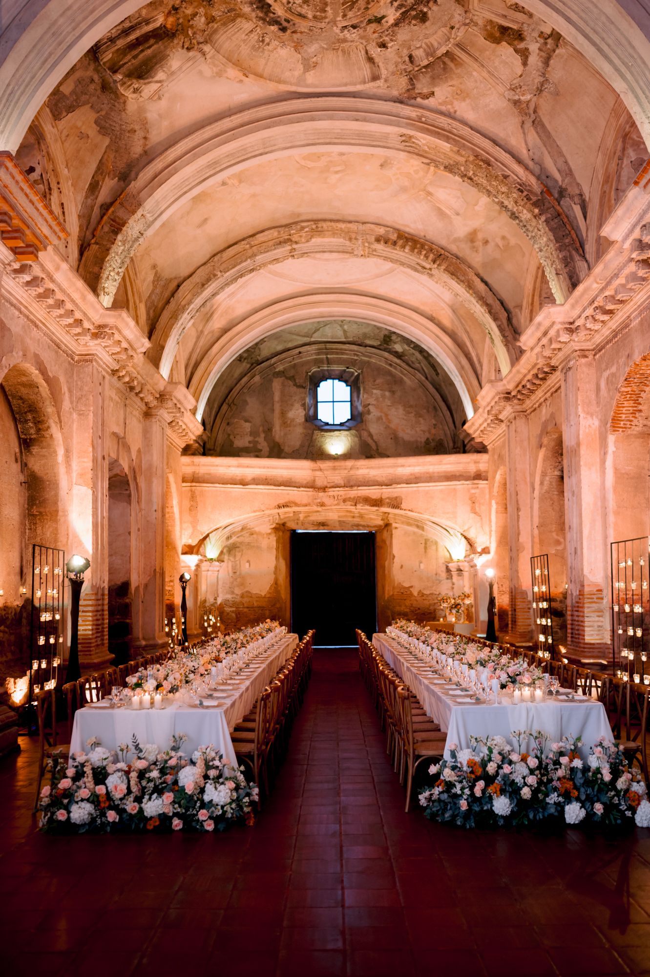 An ornate church interior set up for a wedding reception with long tables and floral arrangements.
