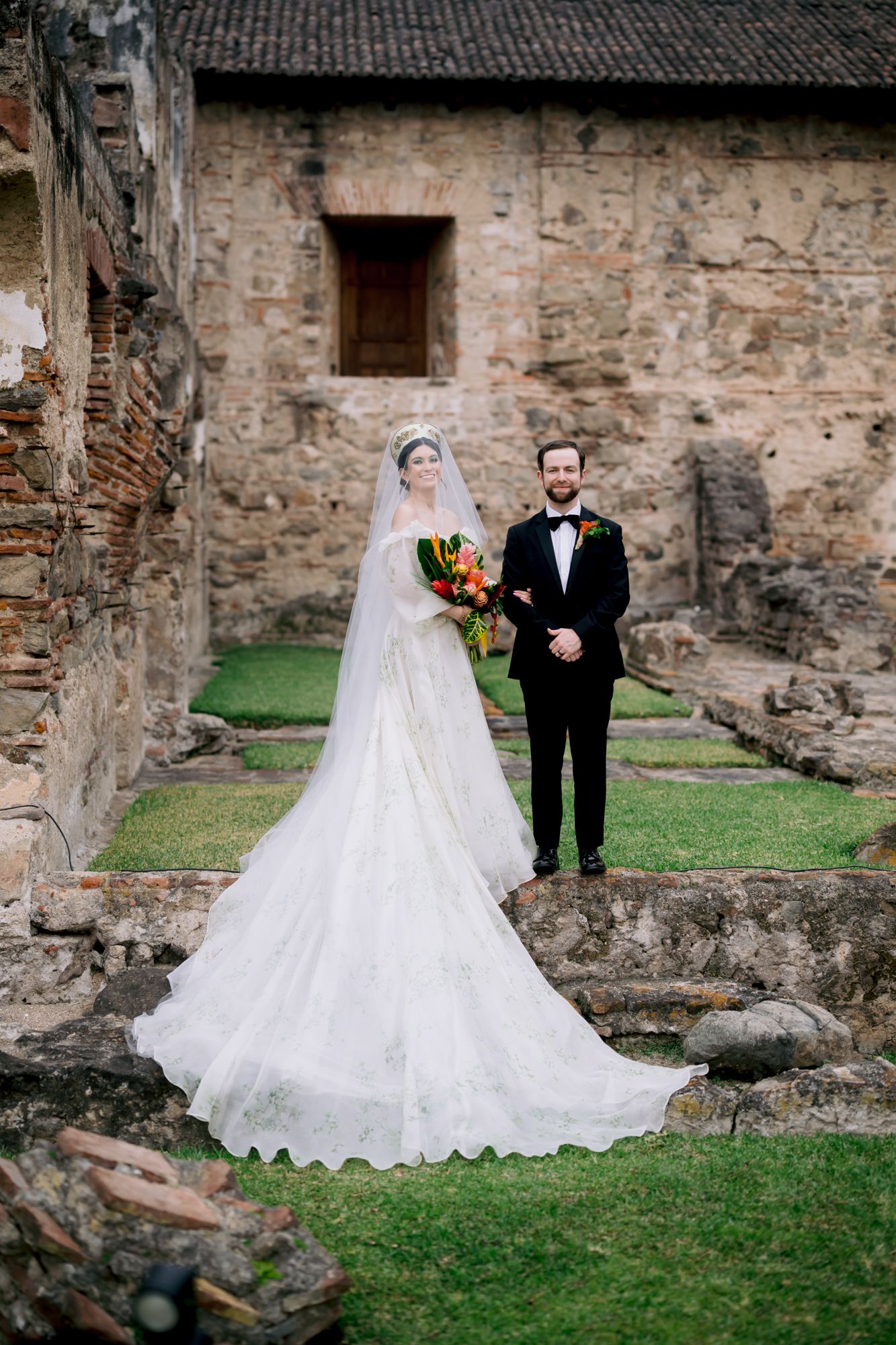 Bride and groom pose for portraits in the ruins of a historic stone building with a flowing wedding gown.