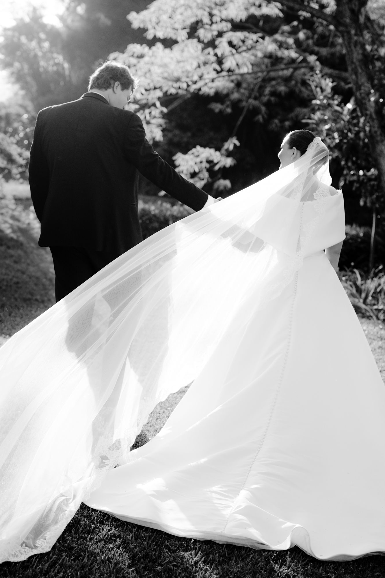 Dramatic black and white photo of a wedding dress flowing in the breeze during an outdoor ceremony.