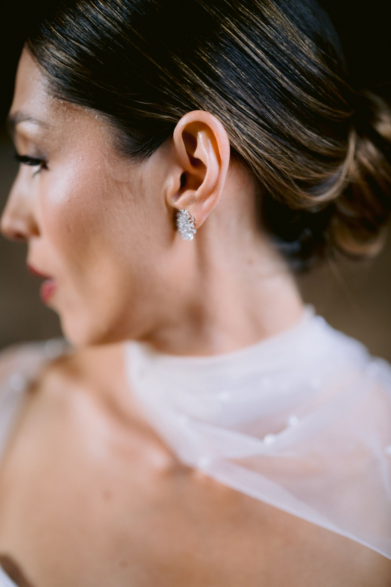 Close-up profile view showing a sparkling crystal earring and delicate tulle veil.