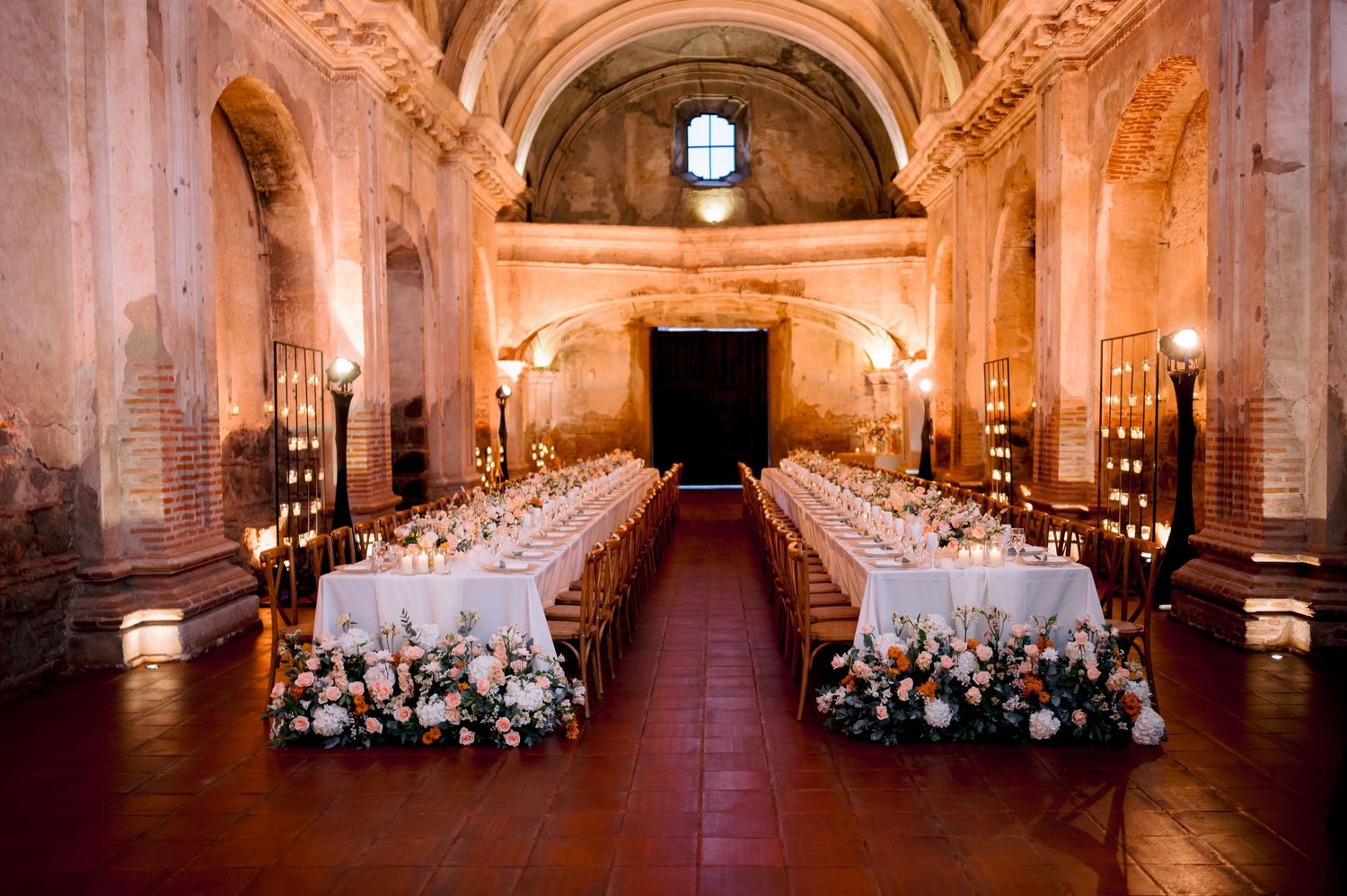 A historic church venue decorated with elegant table settings and floral arrangements for a wedding reception.