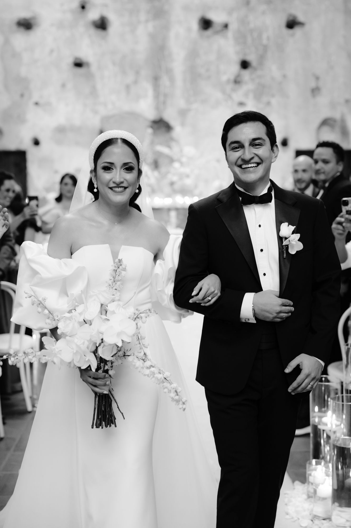 A wedding couple shares a joyful moment during their reception in a black and white photograph.