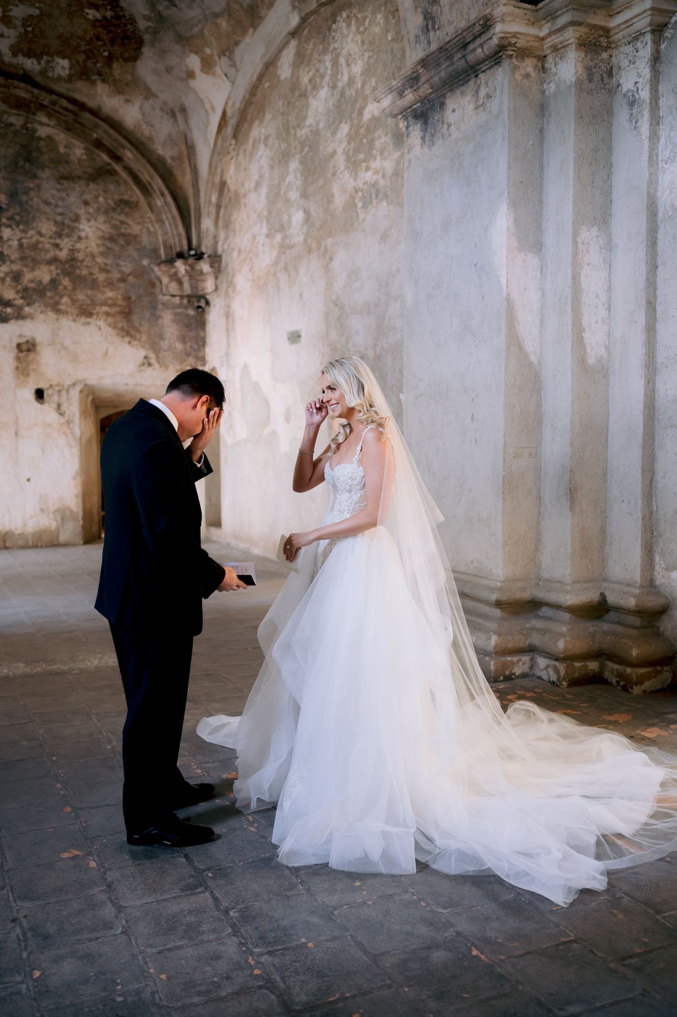 Emotional first look moment between wedding couple in historic stone venue.