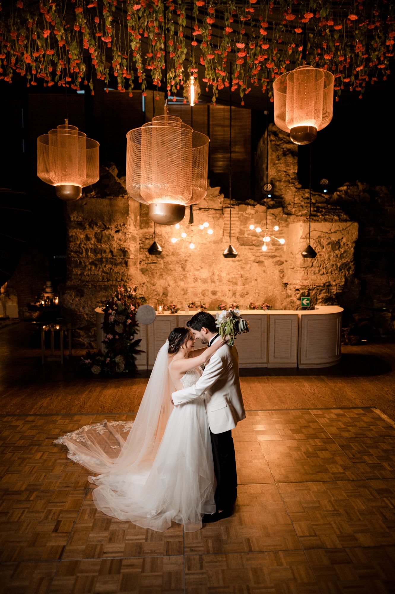First dance under glowing lanterns with romantic ambient lighting and parquet floor.