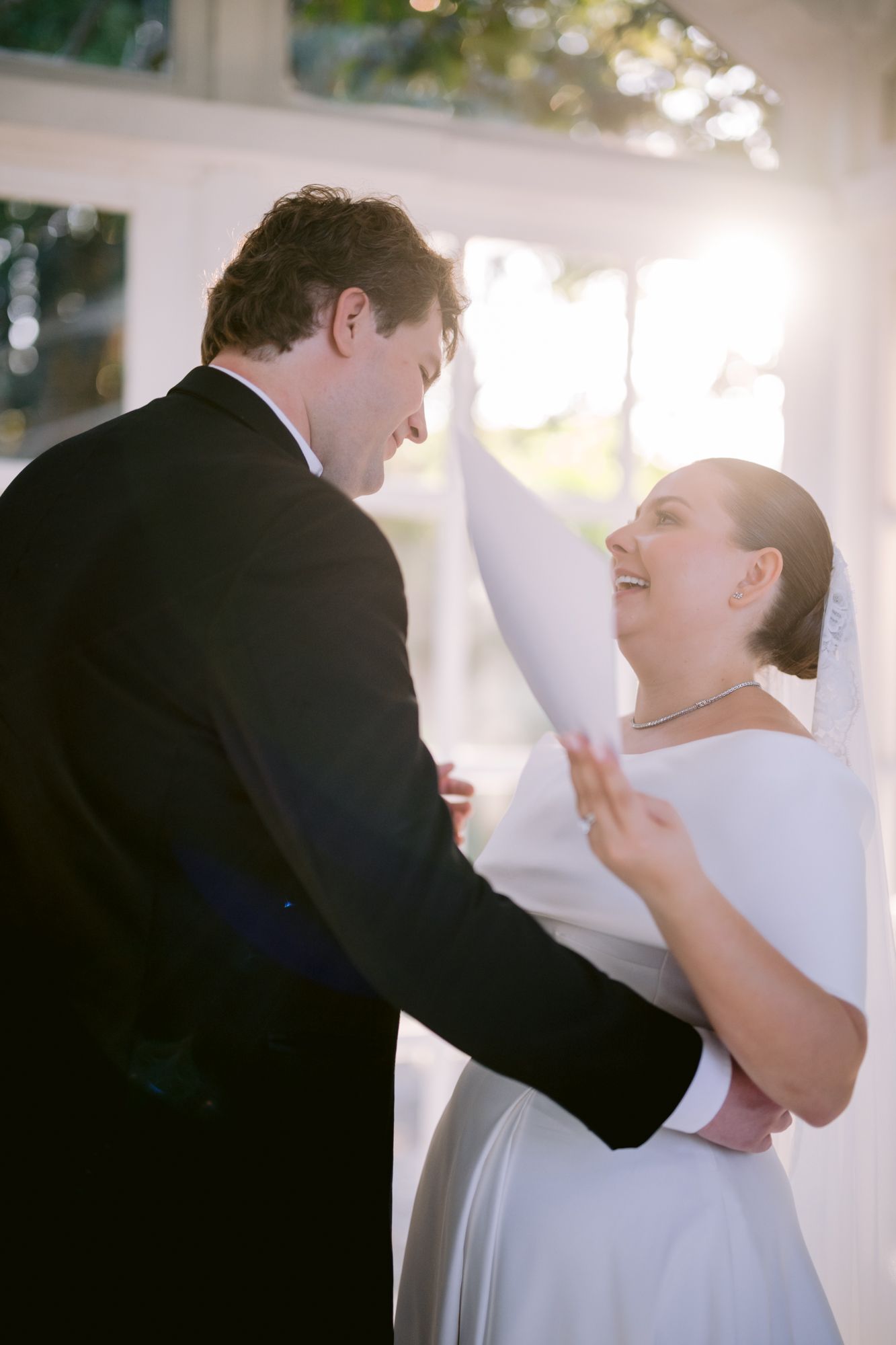 A candid moment of joy and laughter during a wedding ceremony in a bright indoor setting.