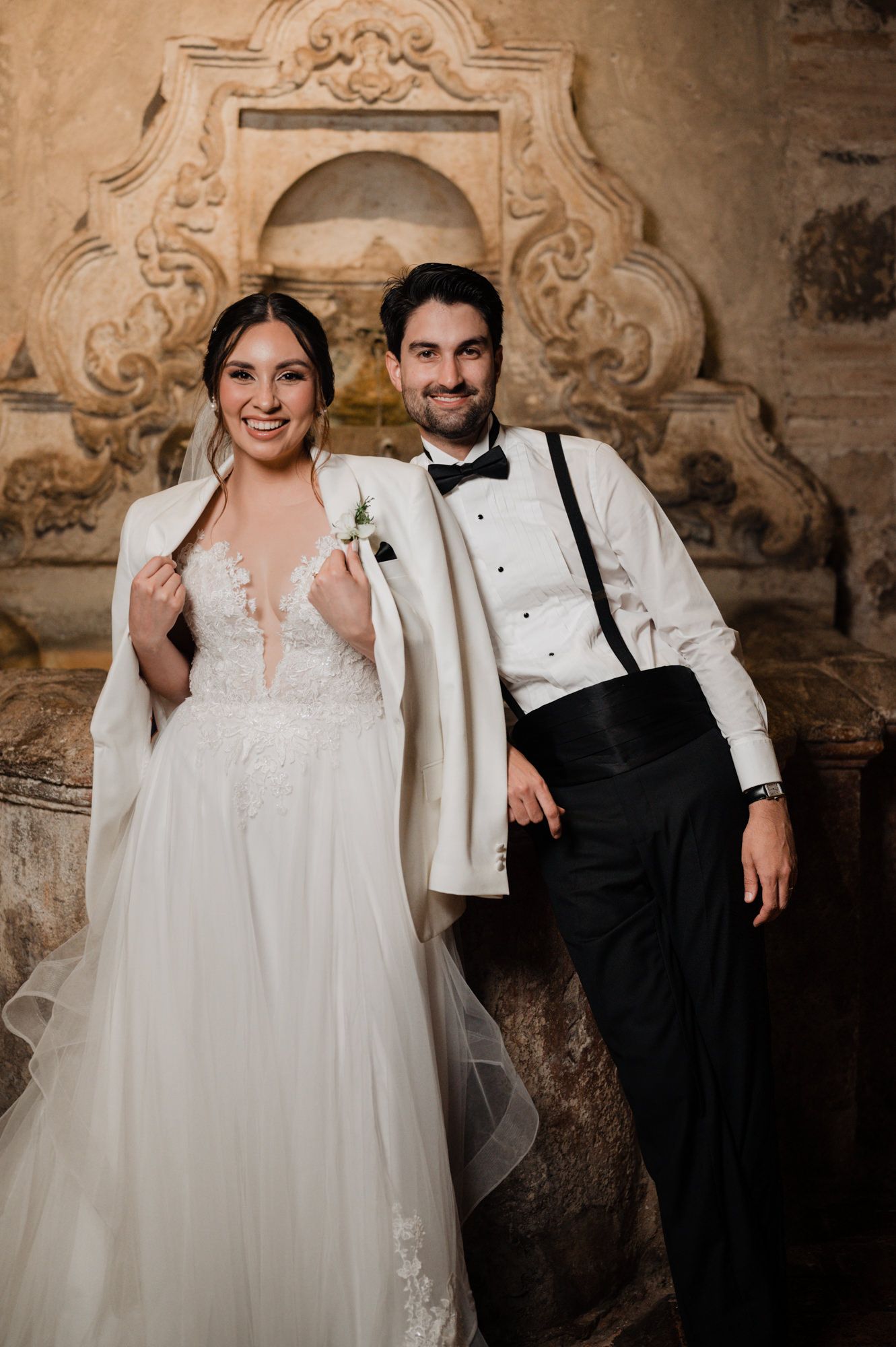 Wedding portrait against ornate stone architectural detail.