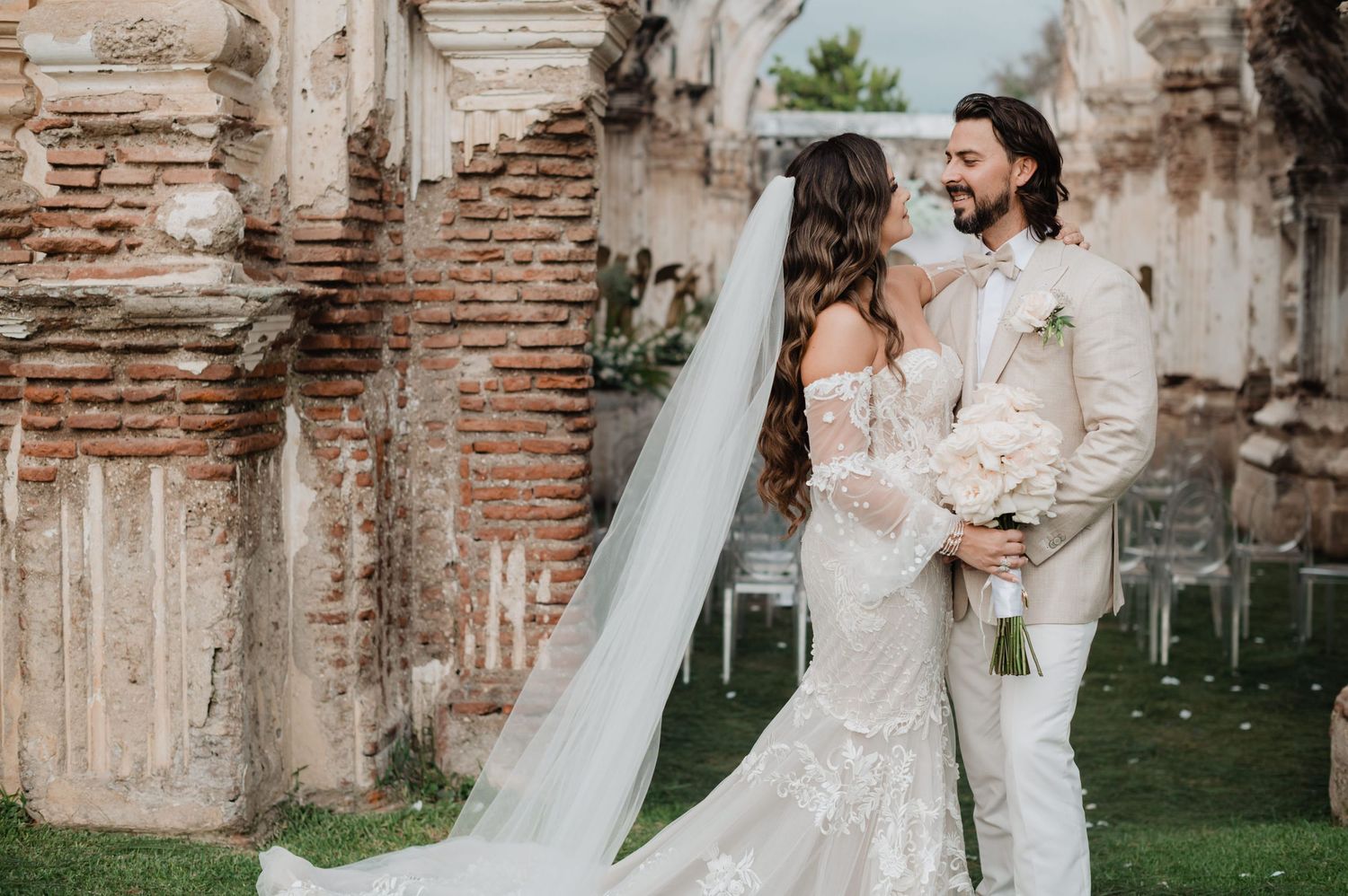A romantic wedding photoshoot takes place under stone arches of a historic ruins site.