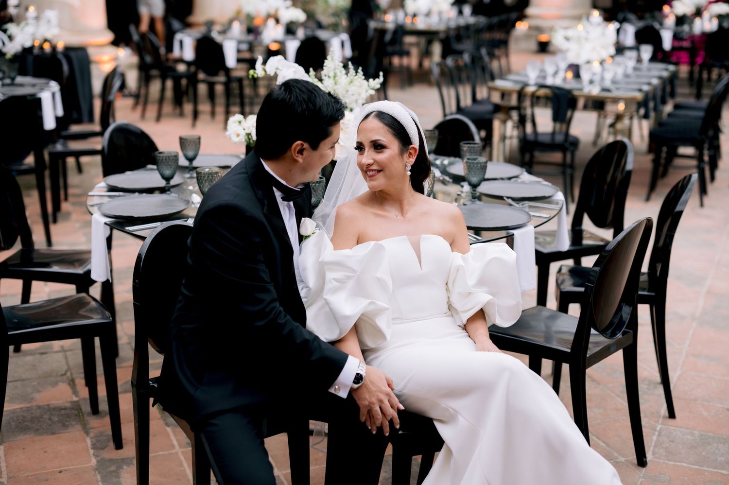 Candid moment between newlyweds seated at outdoor reception venue.