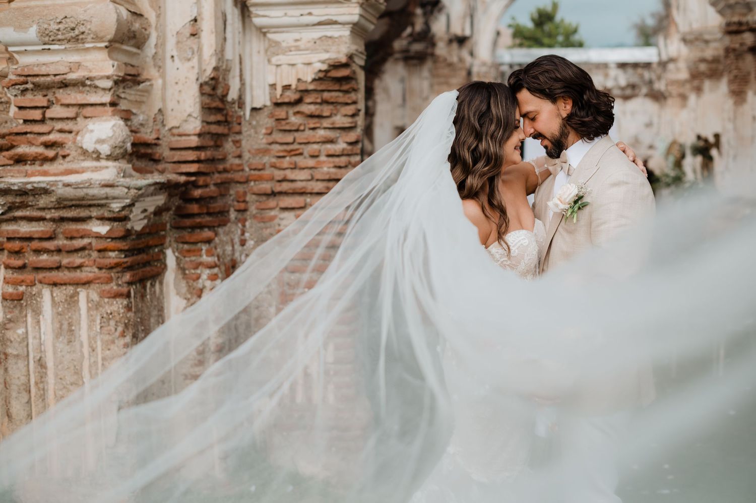 Long bridal veil catches the breeze in an elegant outdoor photo session.