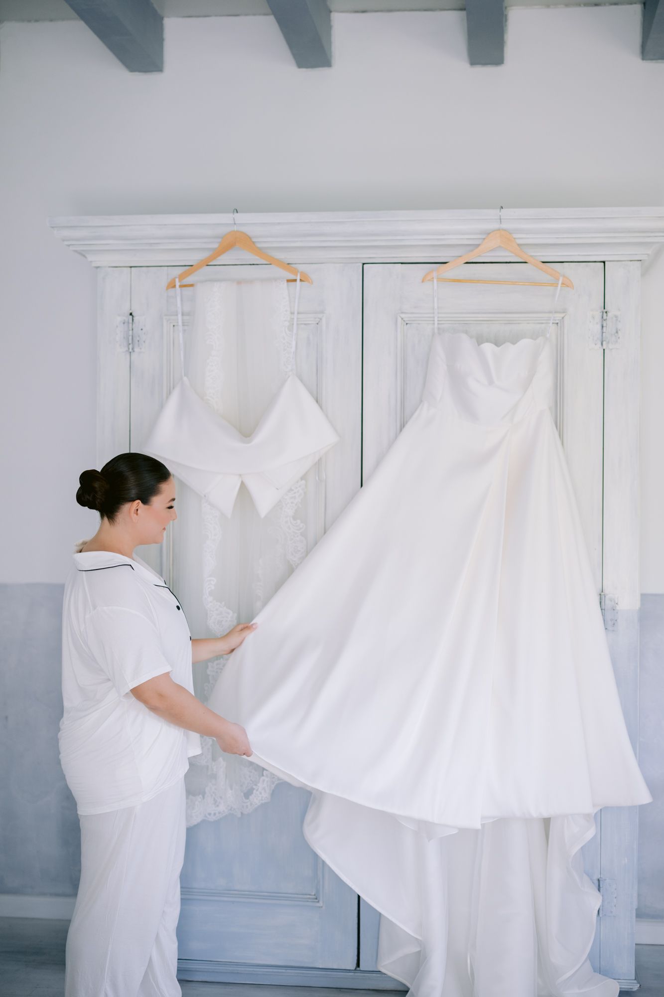 Wedding dress preparations in a room with blue and white walls and wooden hangers.
