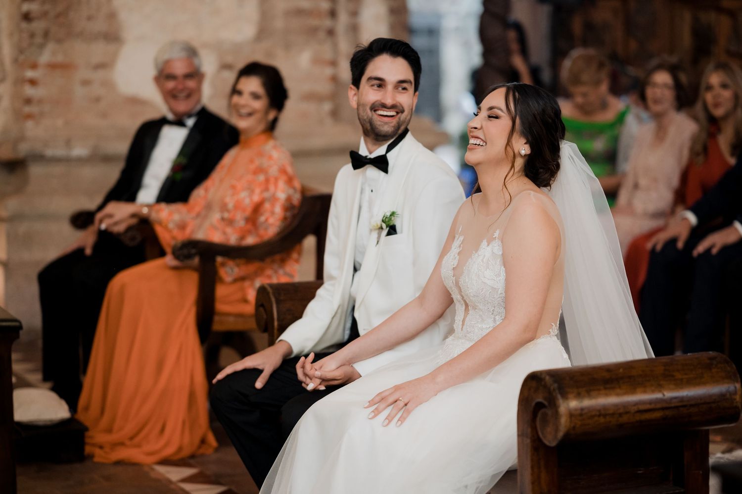 A happy couple sharing a laugh during their wedding ceremony in a historic venue.