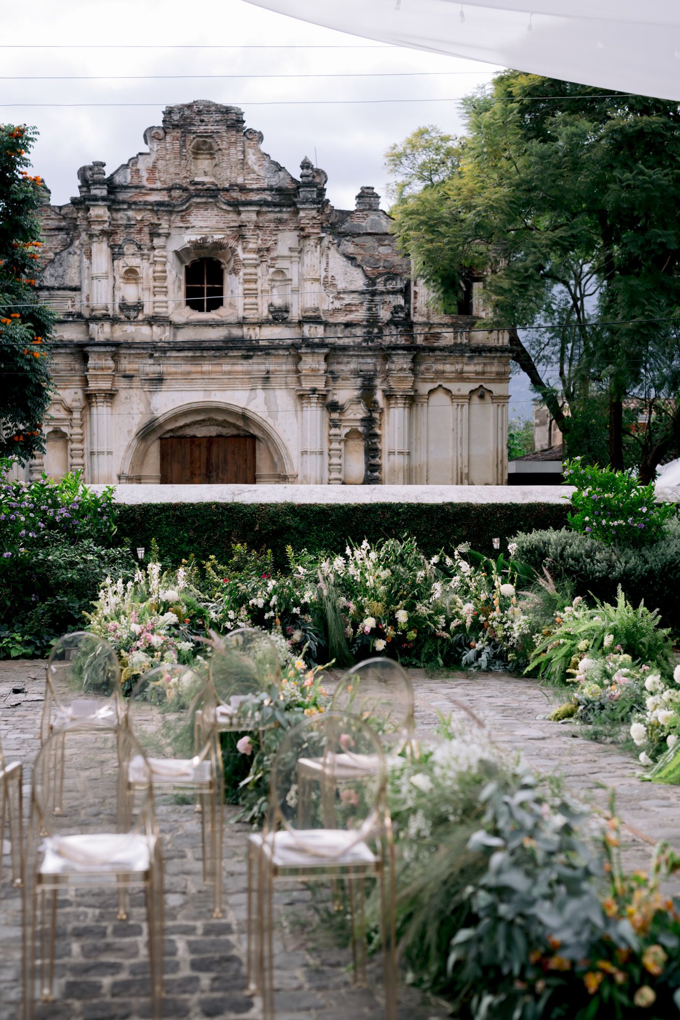 Historic baroque church facade with ornate stone architecture and lush garden landscaping along a stone pathway.