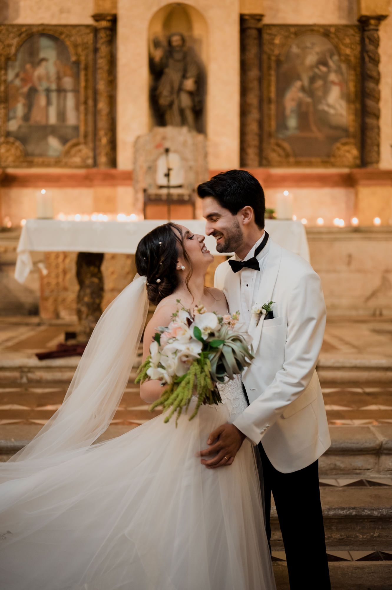 Romantic wedding moment captured in front of historic church altar with beautiful floral bouquet.