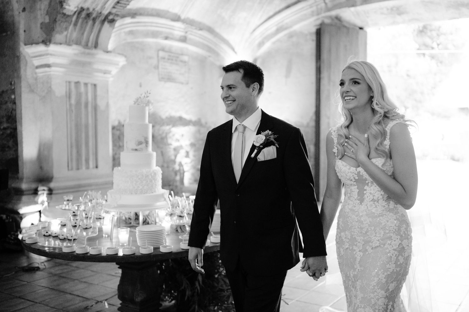 Black and white wedding photo inside historic stone venue with vaulted architecture.