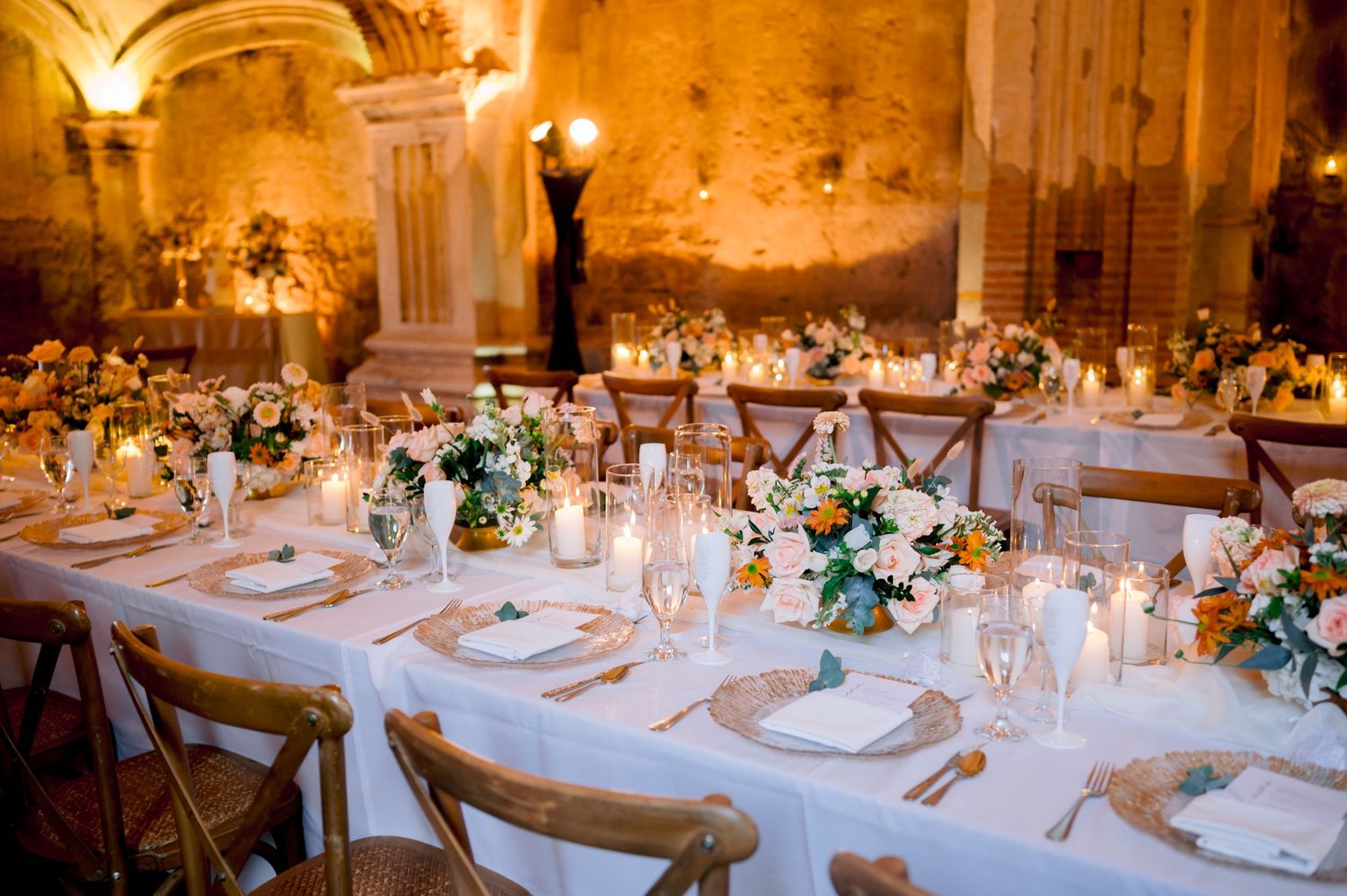 Intimate wedding reception setup with elegant table settings and floral arrangements in rustic chapel.