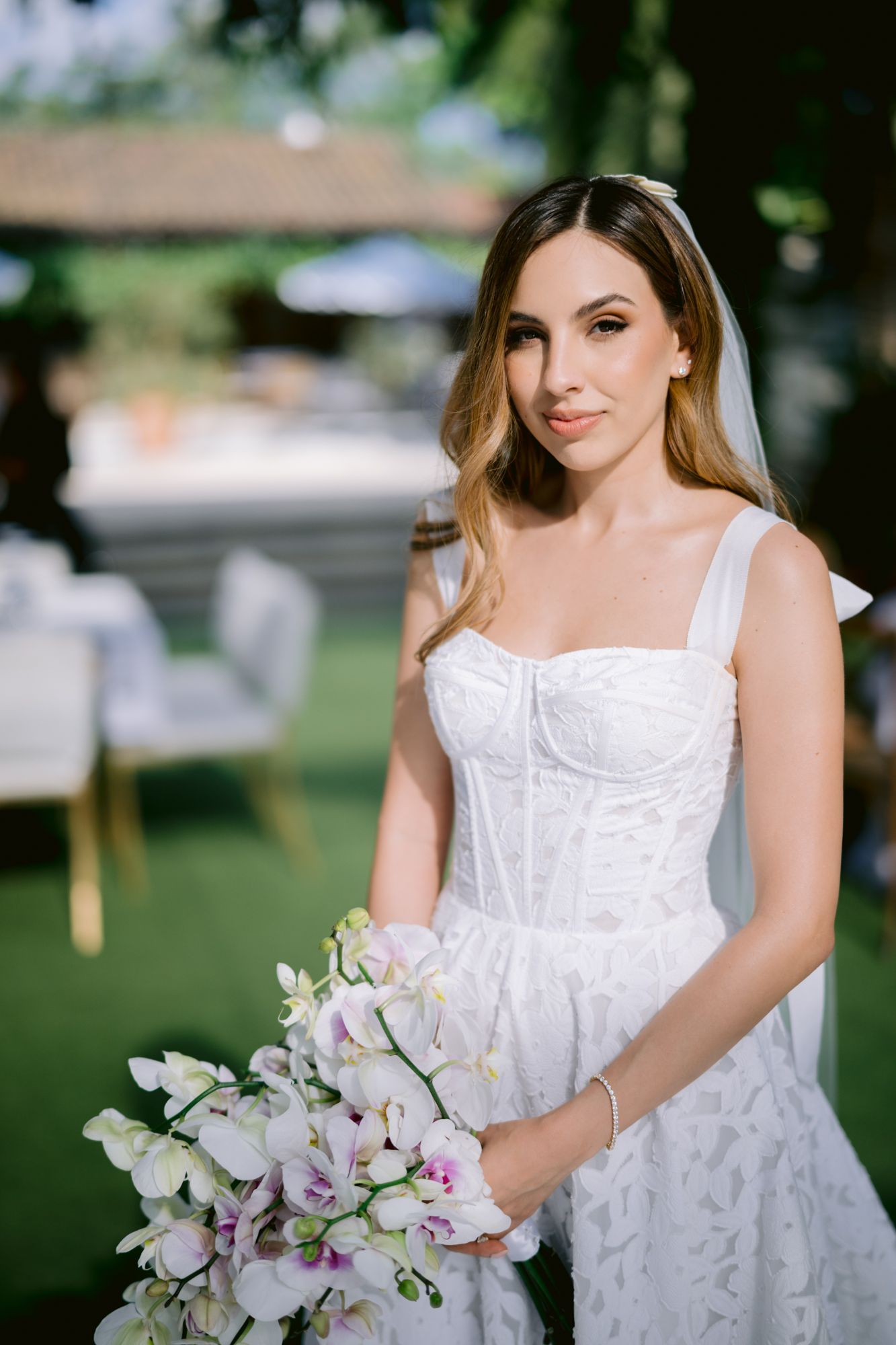 A close-up view of an elegant white wedding dress with a bouquet of pink and white orchids.