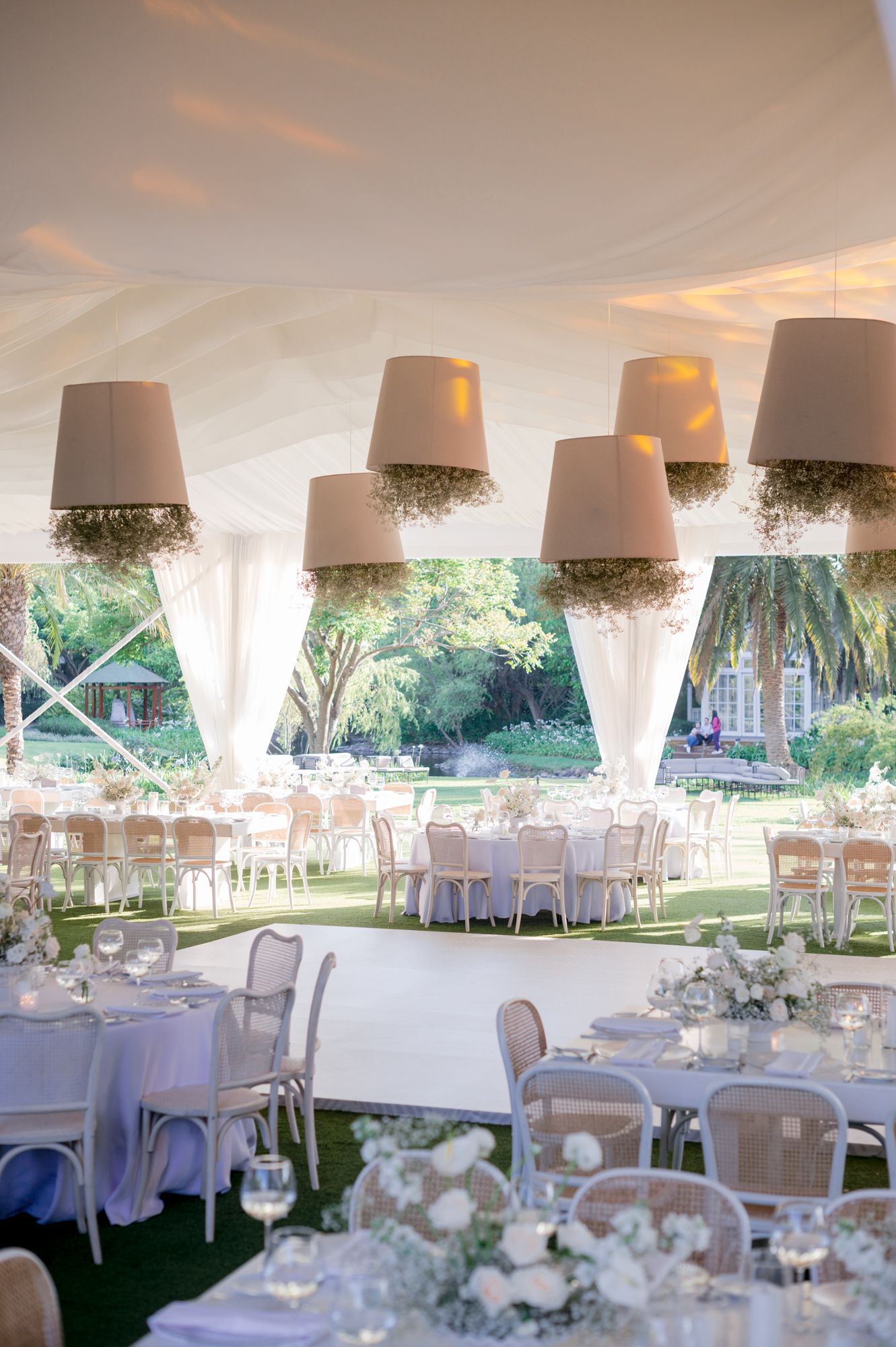 Wedding reception tent with unique inverted lampshade decorations and round tables set for dining.