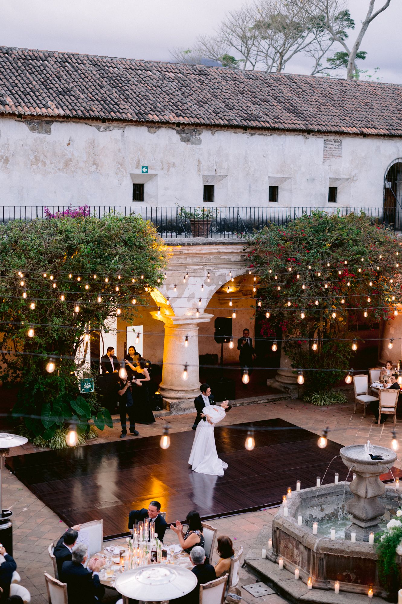 Evening wedding reception in a historic courtyard with string lights and dance floor.