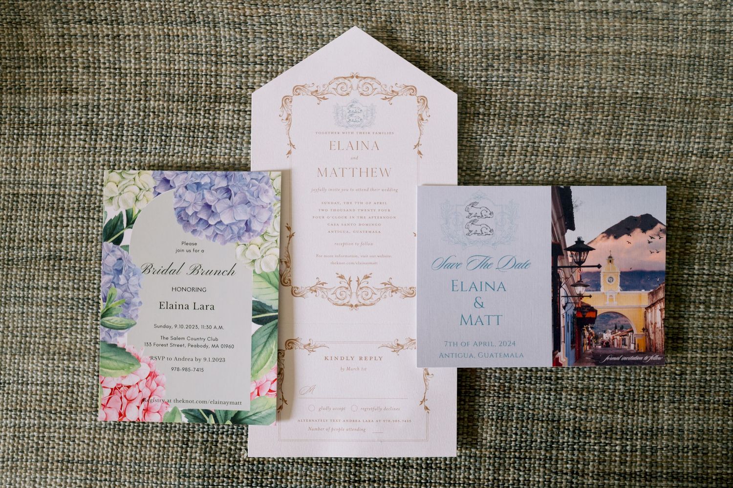 Wedding invitation suite featuring floral designs and blush pink envelopes laid out on textured fabric.