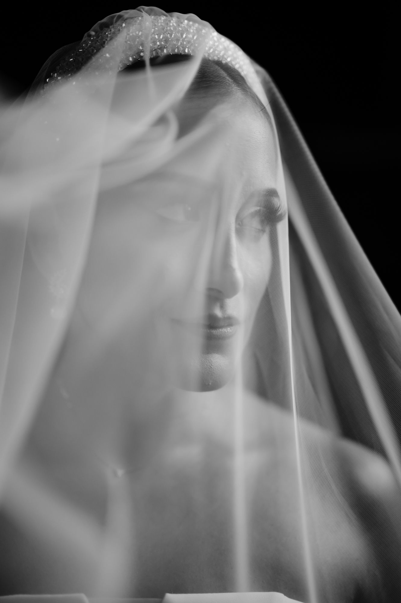 Ethereal black and white portrait of draped figure with veil creating a dreamy, sculptural effect.