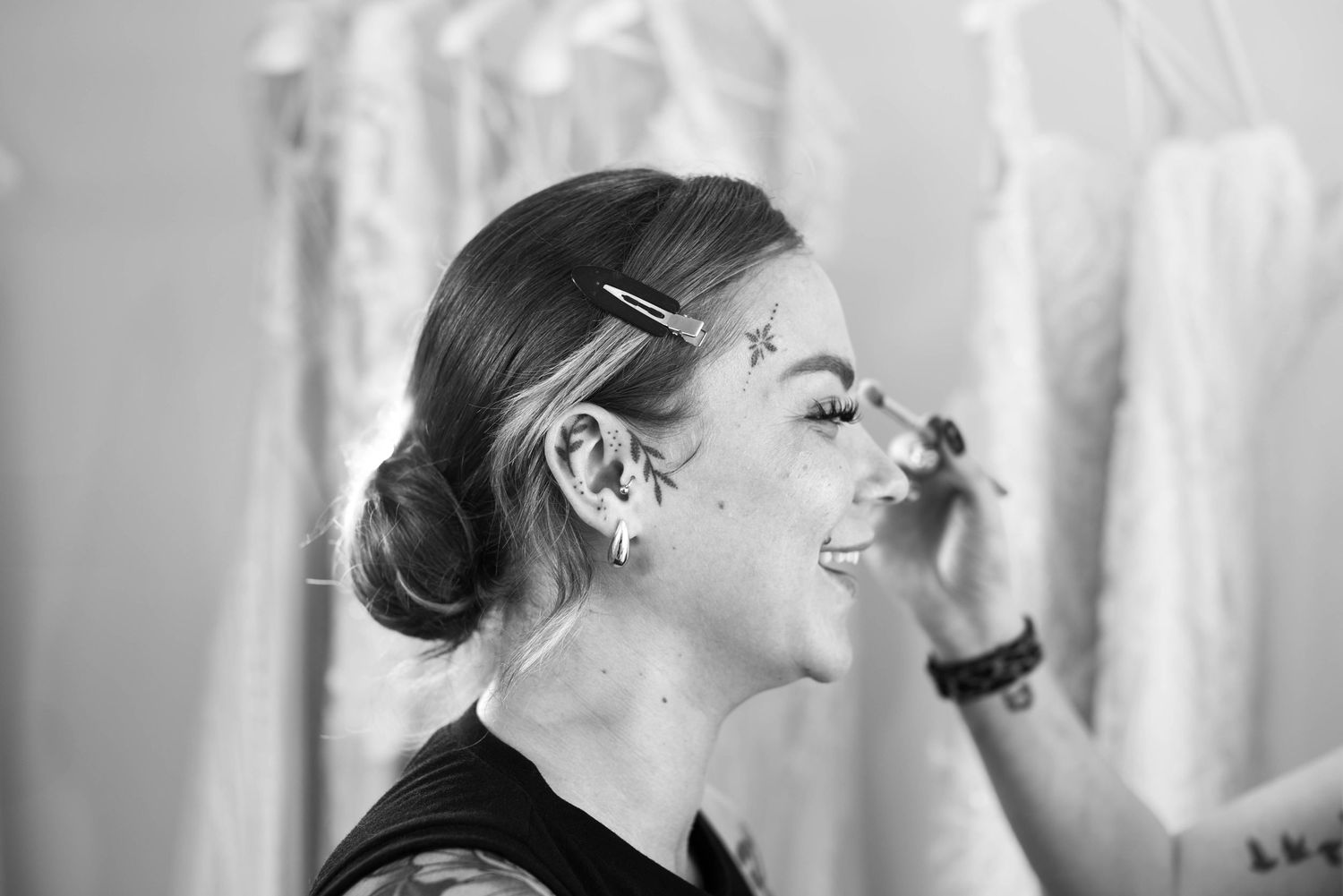 Black and white photo of a smiling woman receiving star face paint makeup application.