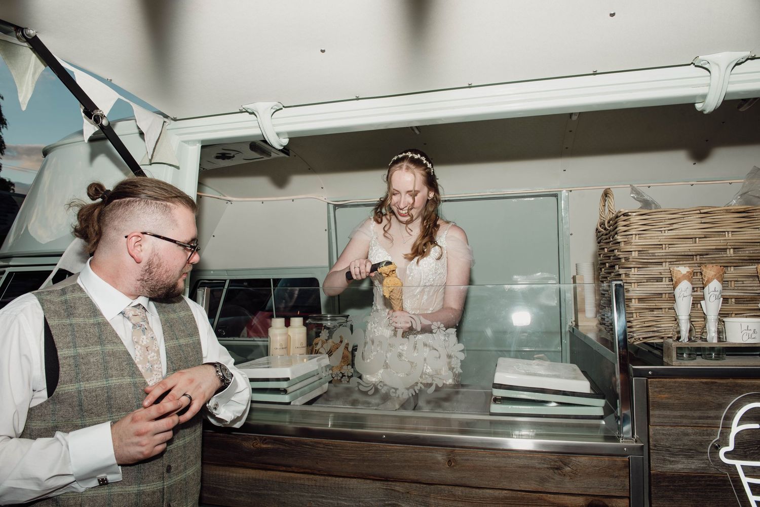 Bride and groom laughing at an ice cream cart during their wedding reception aboard a boat venue.