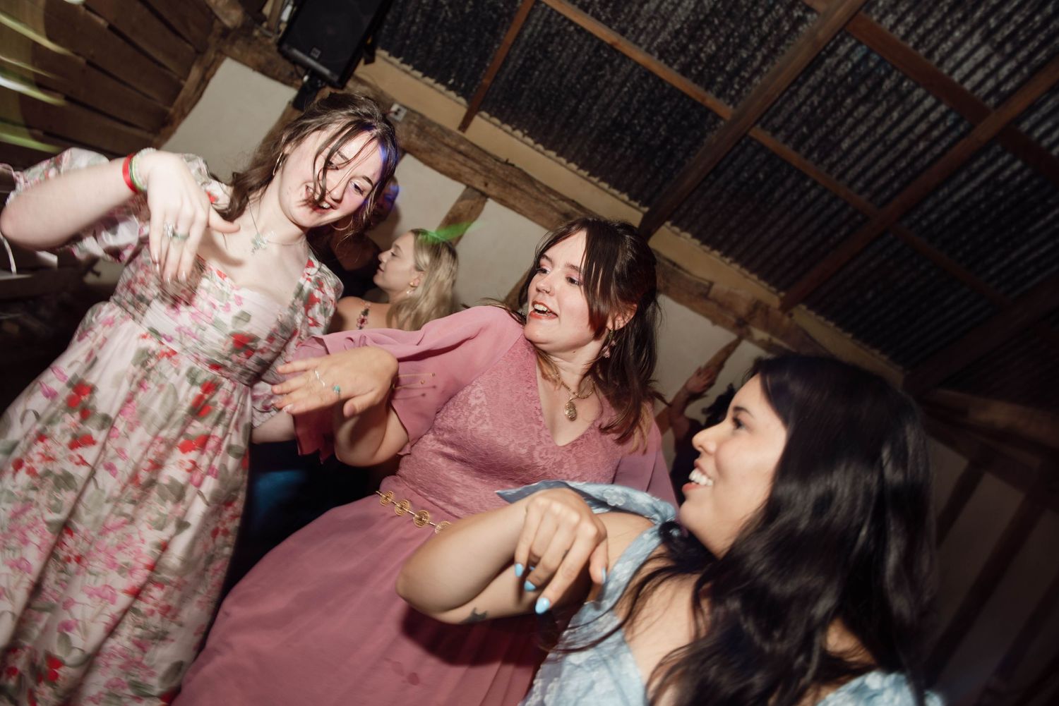 Three women dancing and laughing together at an indoor party celebration.