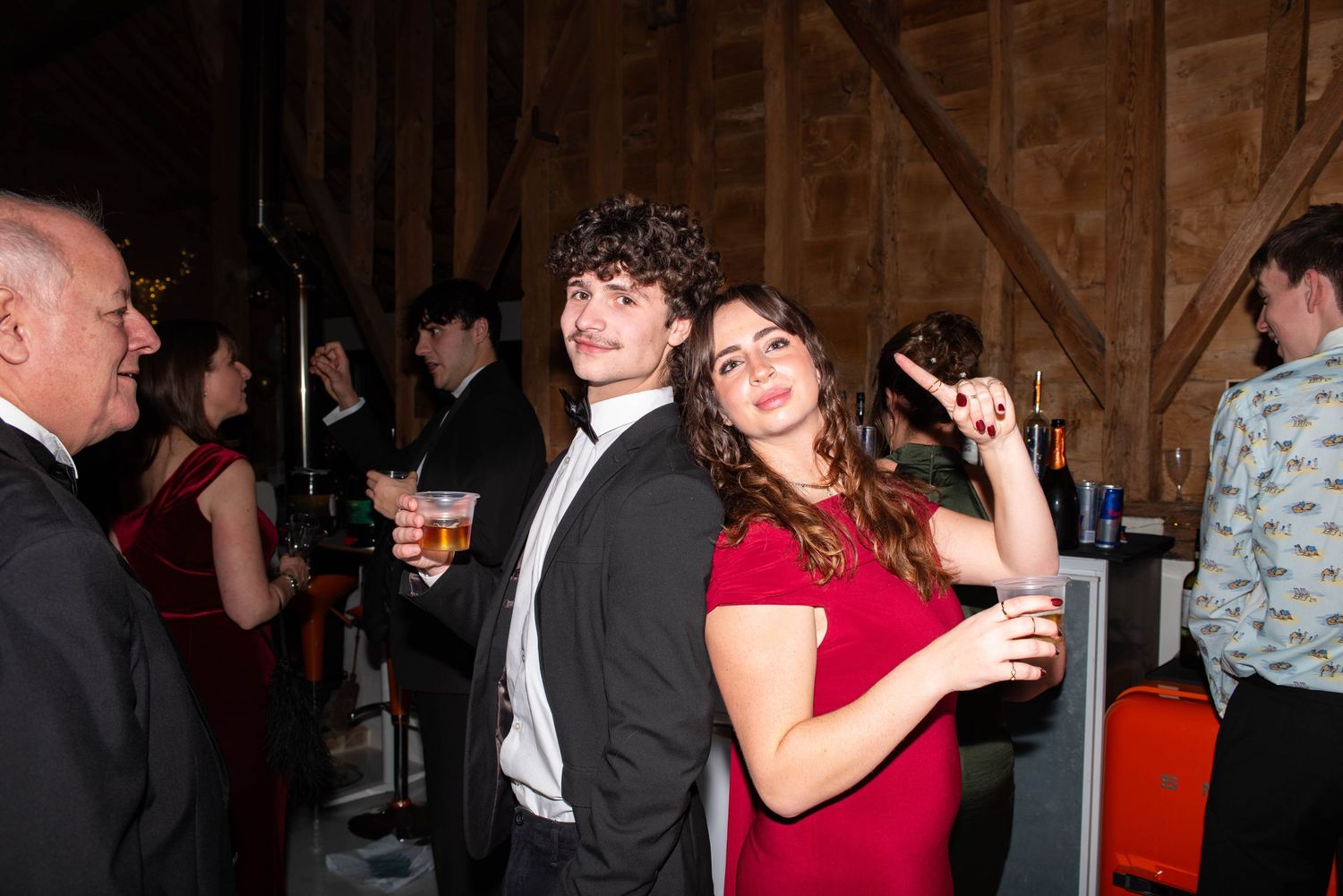 Young couple posing at formal event, man in tuxedo and woman in red dress.