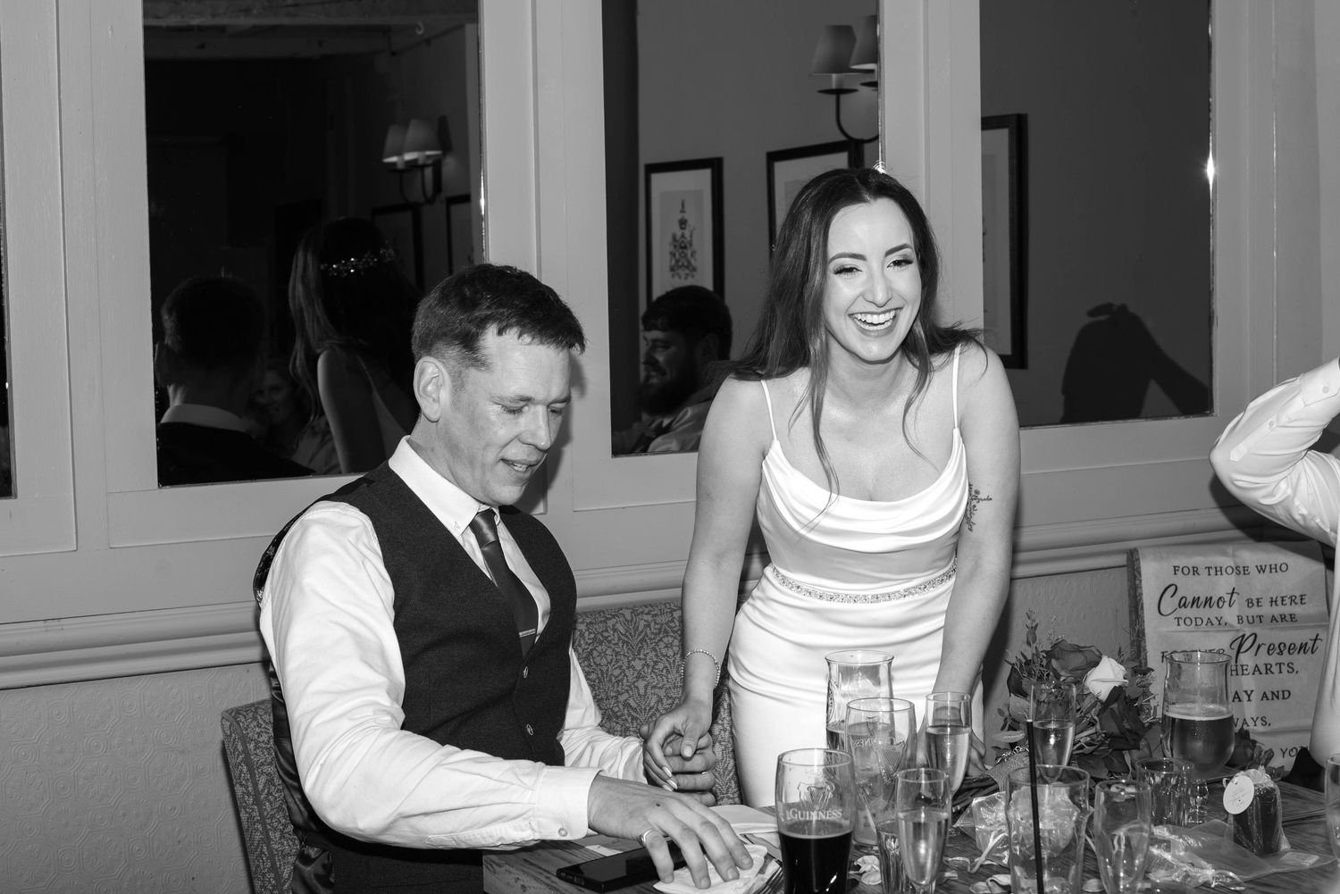 Bride and groom share a joyful moment together at elegantly decorated wedding reception table.