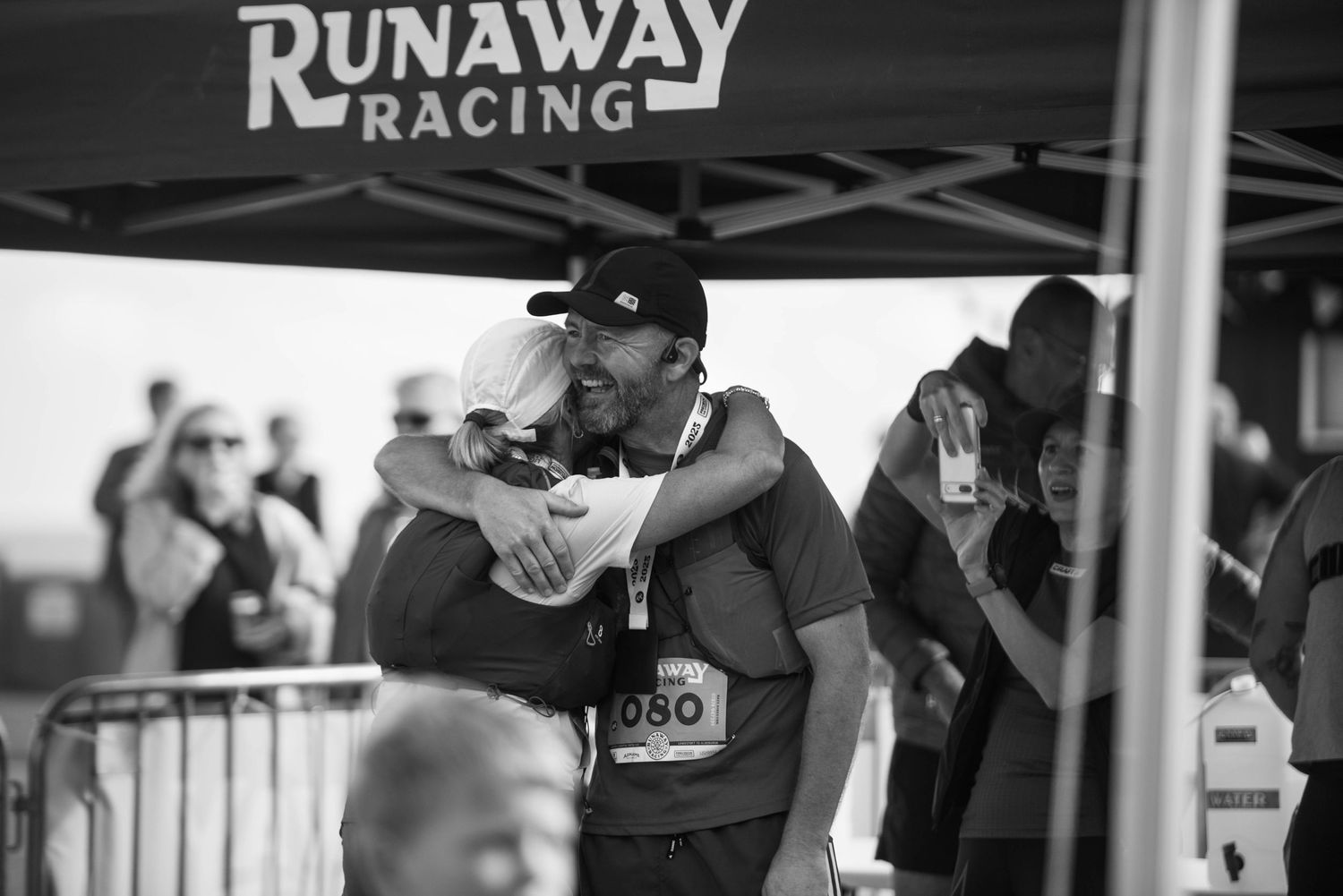 Two people share an emotional hug at a Runaway Racing event in black and white photo.