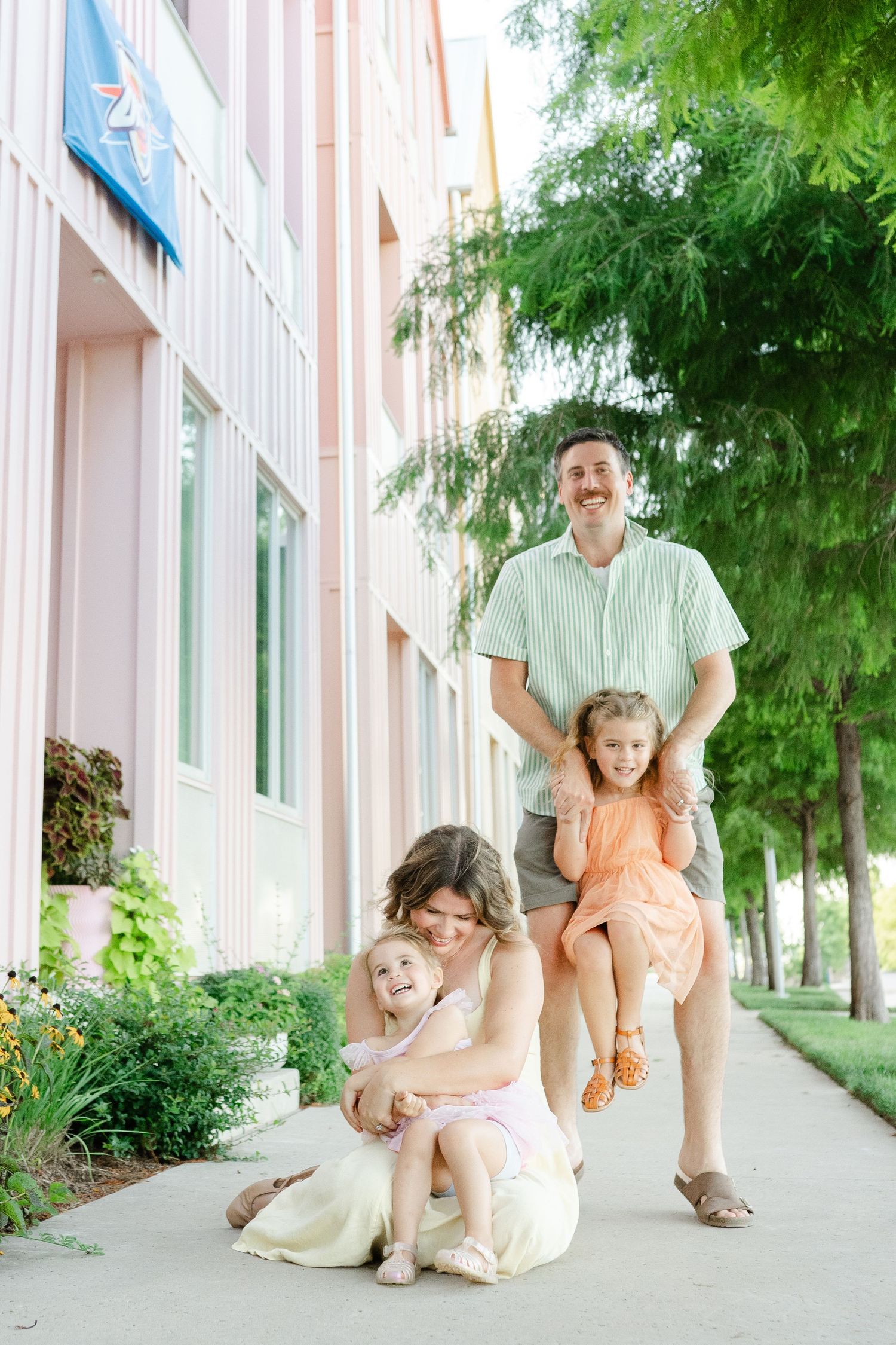 A family poses together on a sidewalk next to a building in the wheeler district in OKC for Oklahoma City Family Photographer